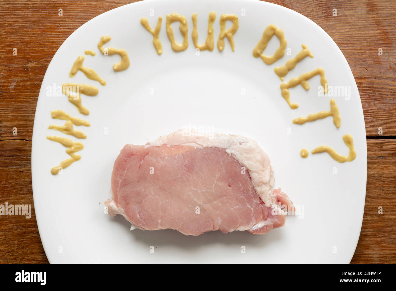 L'humour question écrit par la sauce à la moutarde sur la plaque blanche avec tranche épaisse de la viande de porc cru Banque D'Images