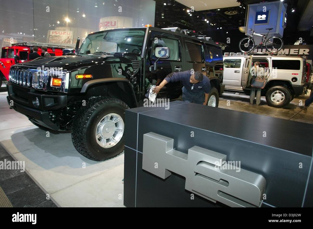 (Afp) - Un employé polit un Hummer H2 par General Motors au Salon international nord-américain (NAIAS) à Detroit, Michigan, le 5 janvier 2004. General Motors, le plus grand fabricant mondial de voitures a réussi à doubler ses bénéfices dans l'exercice 2003 par rapport à 2002. Avec un bénéfice record grâce à la filiale GMAC, de bons chiffres de vente de voitures en Asie une Banque D'Images