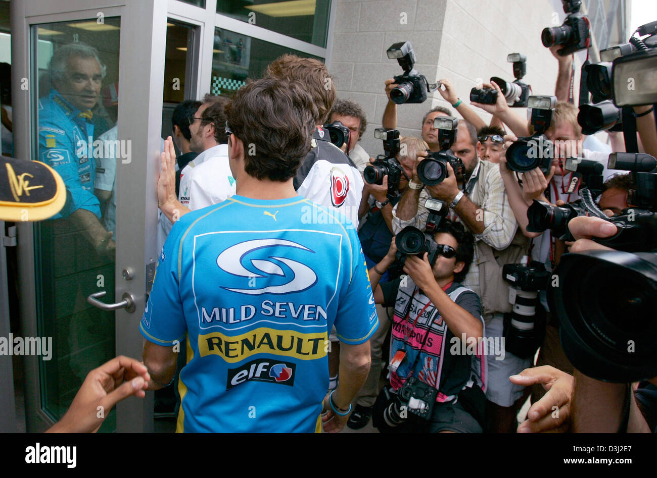 (Afp) - Le directeur principal de l'équipe Renault Flavio Briatore Italienne (L) ouvre la porte pour les pilotes sur leur chemin à une réunion sur la sécurité de la course, qui s'est concentré sur les problèmes causés par les pneus Michelin, avant le début de la Formule Un Grand Prix sur le circuit d'Indianapolis, USA, dimanche 19 juin 2005. Banque D'Images