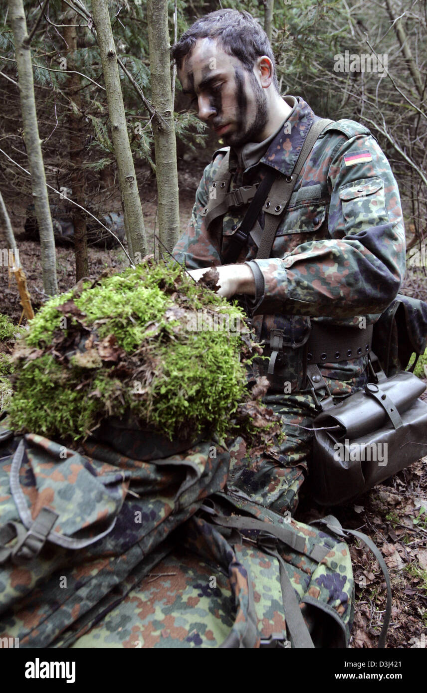 (Afp) - Le fichier photo, datée du 14 avril 2005, montre un appelé camouflant son casque à un exercice sur le terrain dans la forêt au cours de la formation militaire de base à la caserne en Knuell Schwarzenborn, Allemagne, 14 avril 2005. Banque D'Images