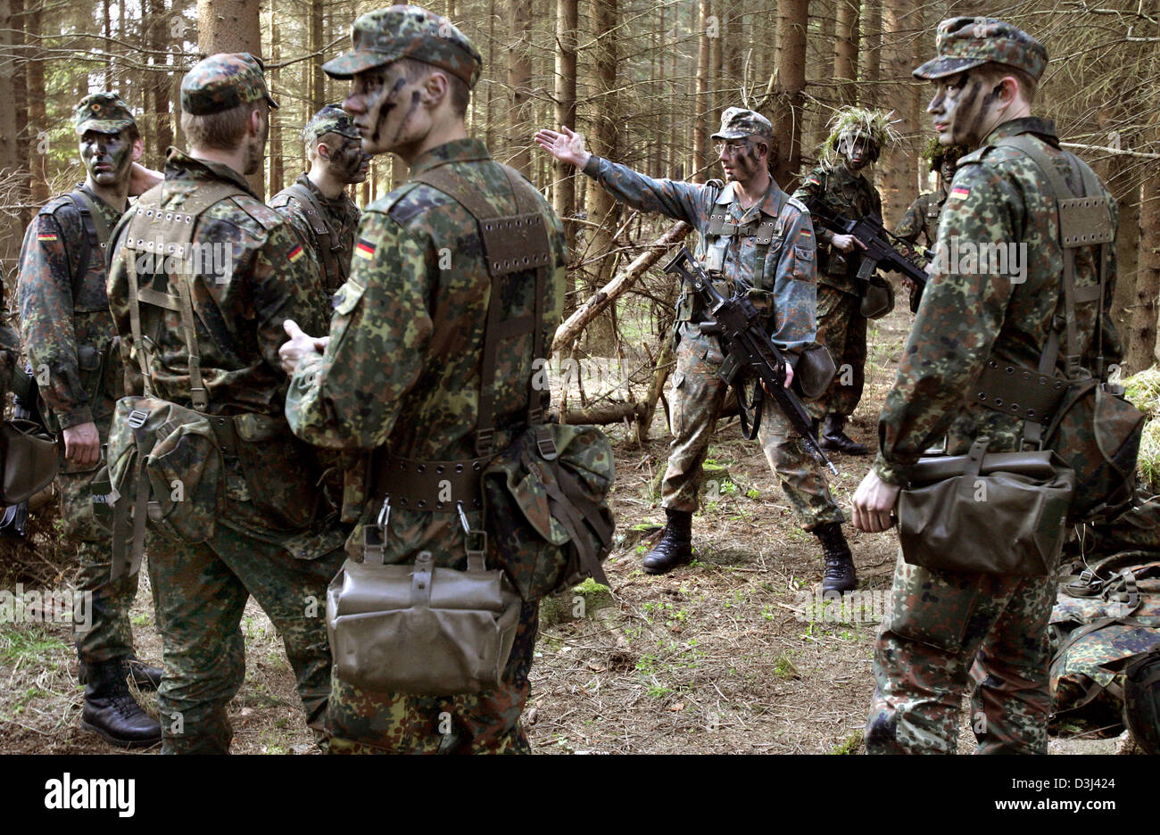 (Afp) - Le fichier photo, datée du 14 avril 2005, montre avec de l'herbe et camouflé les appelés branches de l'instruction de leur instructeur militaire à un exercice sur le terrain dans la forêt au cours de la formation militaire de base à la caserne en Knuell Schwarzenborn, Allemagne, 14 avril 2005. Banque D'Images