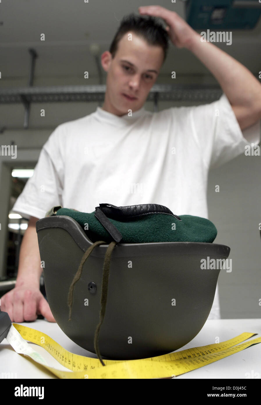 (Afp) - un conscrit regarde son nouveau casque et touche son geled cheveux : vinaigrette de conscrits à la caserne en Knuell Schwarzenborn, Allemagne, 4 avril 2005. Banque D'Images