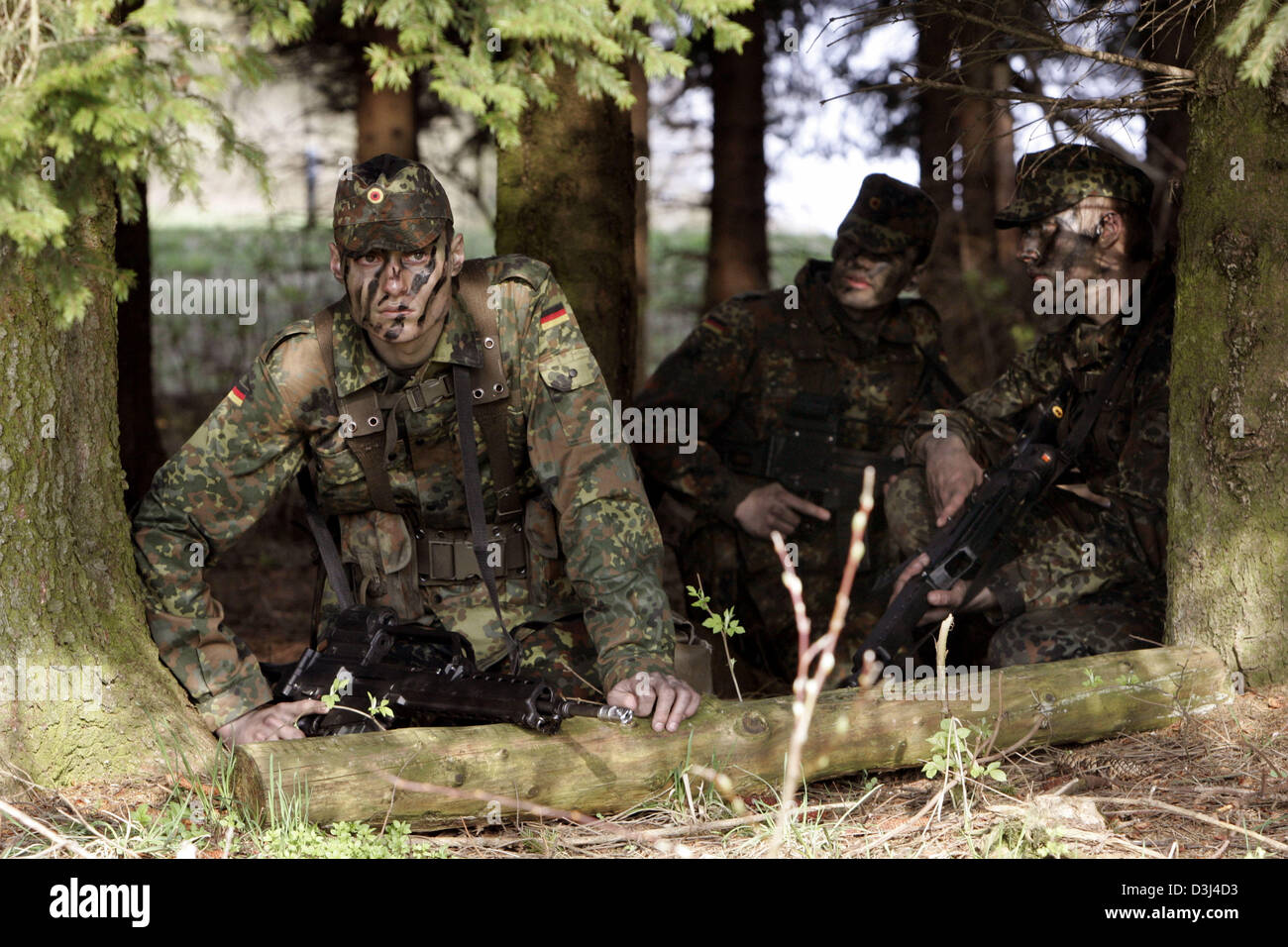 (Afp) - des soldats de l'infanterie blindée de la division de l'armée allemande, avec des visages peints, une tenue de camouflage et armés de fusils g36, se mettre à couvert pendant un exercice sur le terrain dans le cadre de la formation militaire de base à la caserne en Knuell Schwarzenborn, Allemagne, 14 avril 2005. Banque D'Images