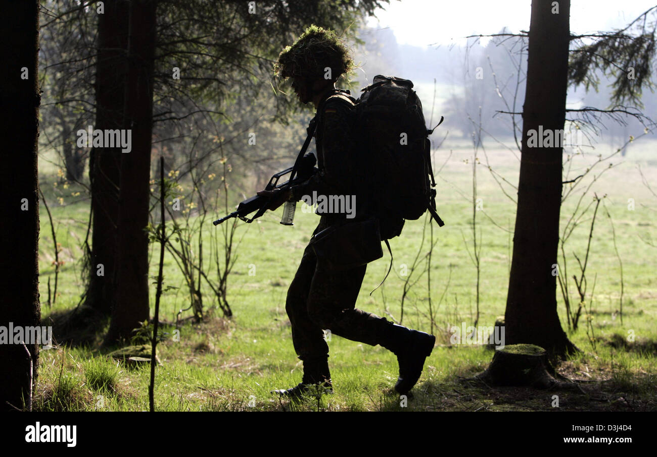 (Afp) - Un soldat camouflé de la division d'infanterie de la Bundeswehr, armée d'un fusil G36, marche à travers une forêt au cours d'un exercice sur le terrain dans le cadre de la formation militaire de base à la caserne en Knuell Schwarzenborn, Allemagne, 14 avril 2005. Banque D'Images