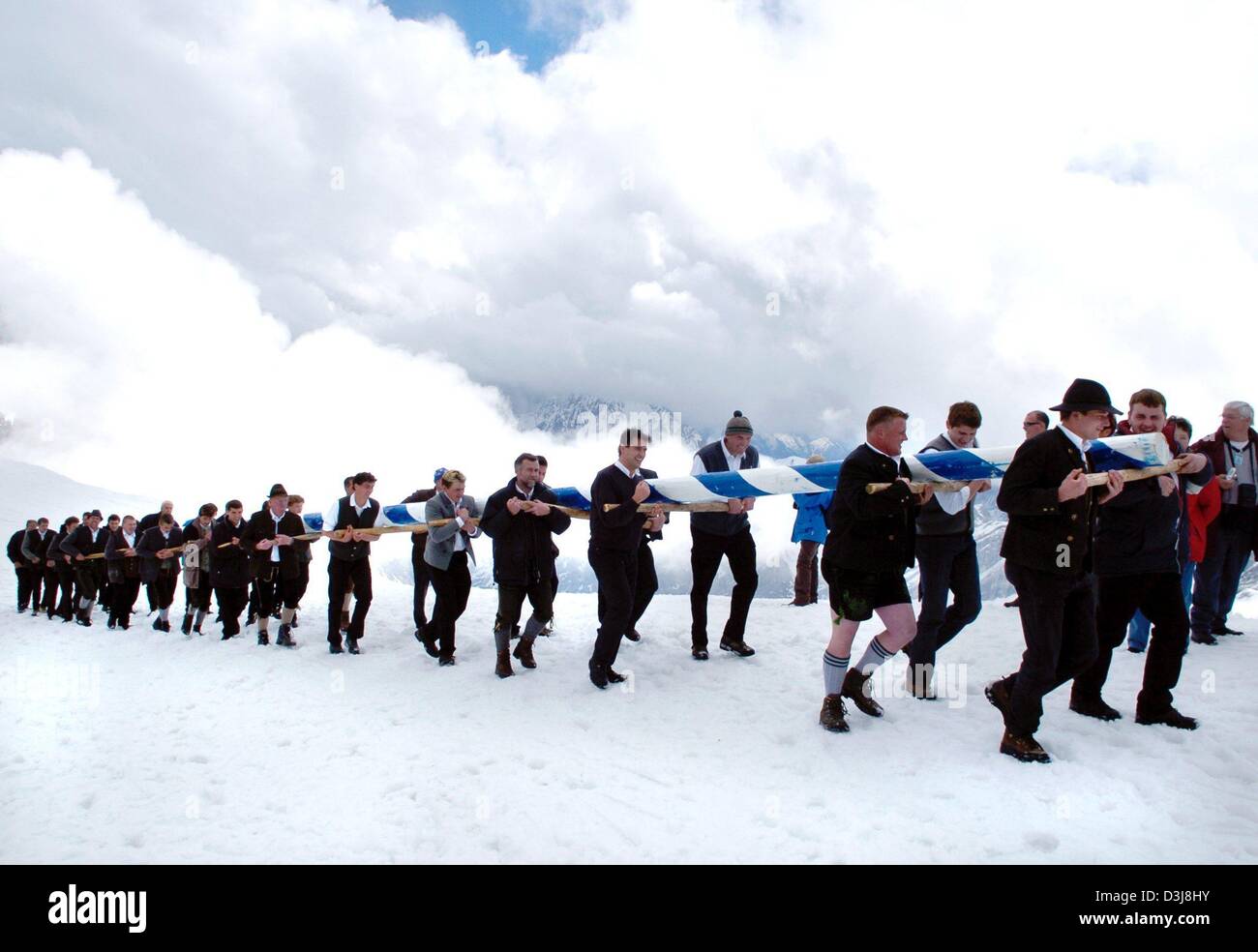 (Afp) - avec d'épais nuages en arrière-plan les membres de fraternité transporter un mât à une altitude de 3 000 mètres à son endroit désigné sur la montagne Zugspitze en Allemagne le 1 mai 2004. Le mât le plus grand du monde a été érigée en début d'après-midi. Banque D'Images