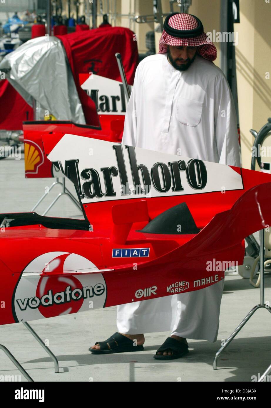 (Afp) un homme en habit traditionnel observe un cache moteur Ferrari de l'Allemand F1 champion du monde en titre Michael Schumacher sur le nouveau circuit de F1 de Bahreïn le mercredi, 31 mars 2004. Le dimanche, 4 avril 2004, le Grand Prix de Bahreïn sera démarré. Banque D'Images