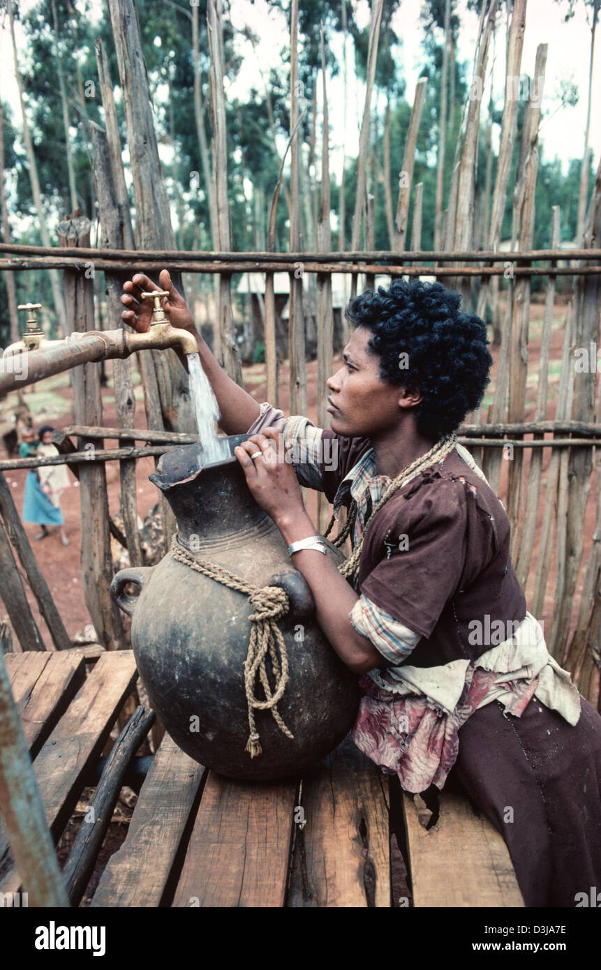 Une femme éthiopienne remplit son réservoir d'eau à un robinet d'eau communautaire à la périphérie d'Addis-Abeba, en Éthiopie Banque D'Images