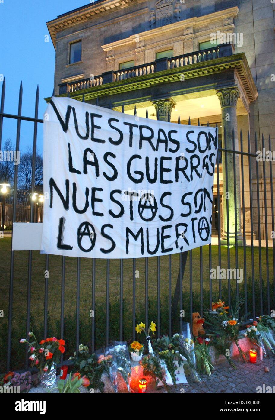 (Afp) - Une bannière est suspendu au-dessus des bouquets de fleurs et de bougies attaché à une clôture entourant l'ambassade d'Espagne à Berlin, 14 mars 2004. La bannière indique 'Vuestras las Guerras, nuestros fils fils los muertos" (votre guerre et nos morts). Environ 30 personnes se sont réunies pour un rassemblement pour protester contre la politique du gouvernement espagnol. 200 personnes sont mortes et plus de 1 200 ont été blessés dans un Banque D'Images