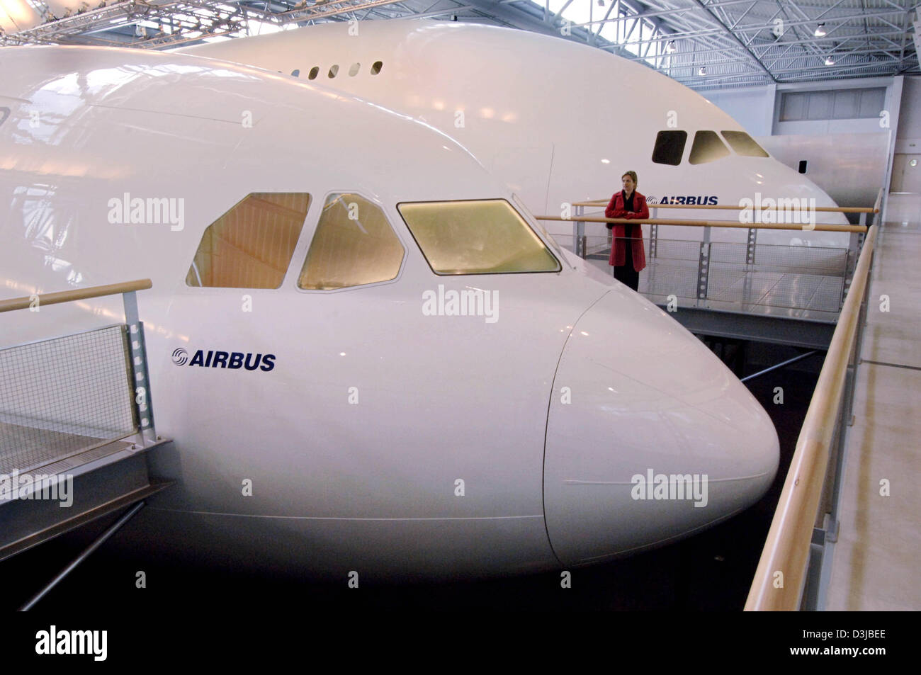Afp) - une femme dans un manteau rouge ressemble à un grand modèle  (maquette) de l'Airbus A340 (avant) au siège social d'Airbus à Toulouse,  France, 20 avril 2005. Dans l'arrière-plan est une