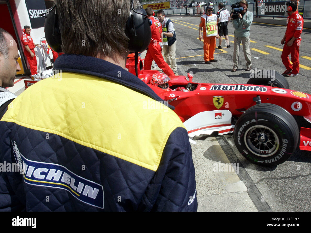 (Afp) -Un technicien (L) des pneus Michelin et contrôleurs allemand pilote de Formule 1 Michael Schumacher Ferrari de quitter la fosse dans sa voiture de sport à la Formule Un de course à Imola, Italie, le vendredi 22 avril 2005. Le Grand Prix de Saint-Marin va commencer ici dimanche 24 avril 2005. Banque D'Images