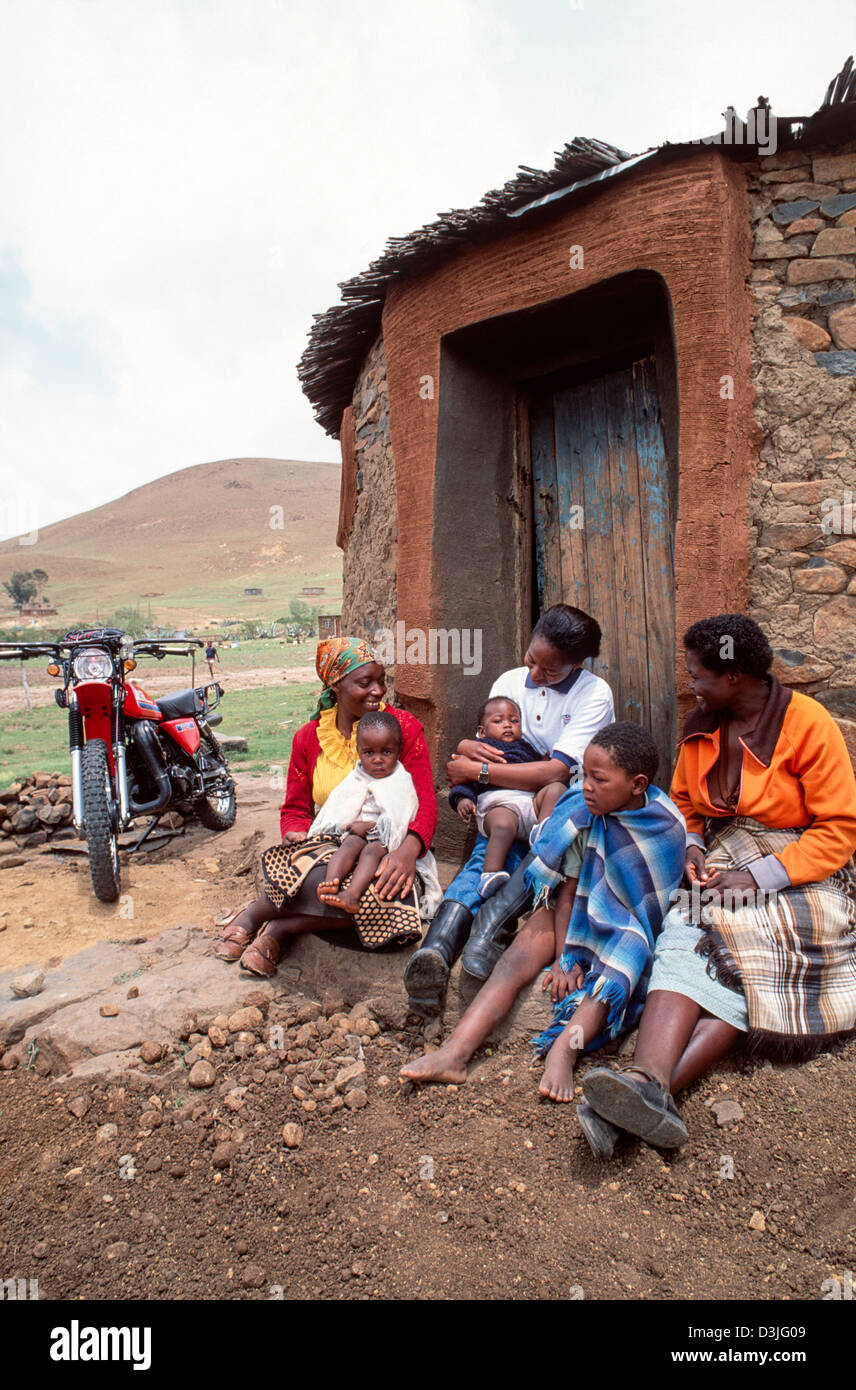 Une infirmière communautaire avec sa moto dans le cadre du programme Riders for Health visite des femmes et des enfants dans une ferme rurale éloignée, près de Mafeteng, au Lesotho Banque D'Images