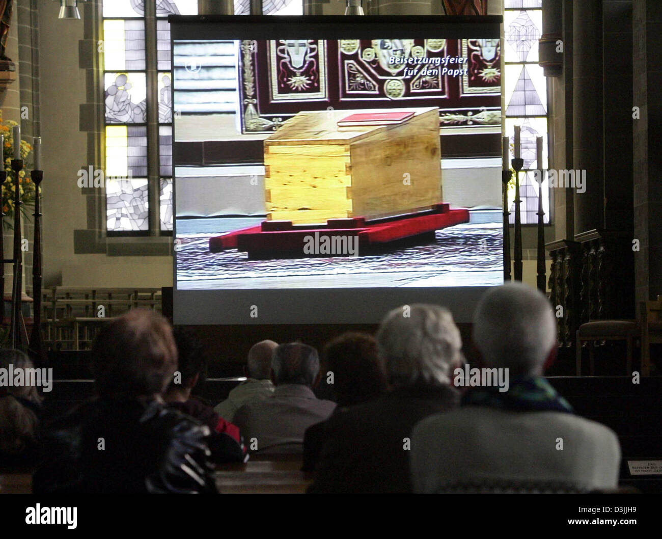 (Afp) - Les croyants regarder la télévision de transmission aux obsèques du pape Jean Paul II sur un écran vidéo à la cathédrale d'Essen, Allemagne, 8 avril 2005. Banque D'Images