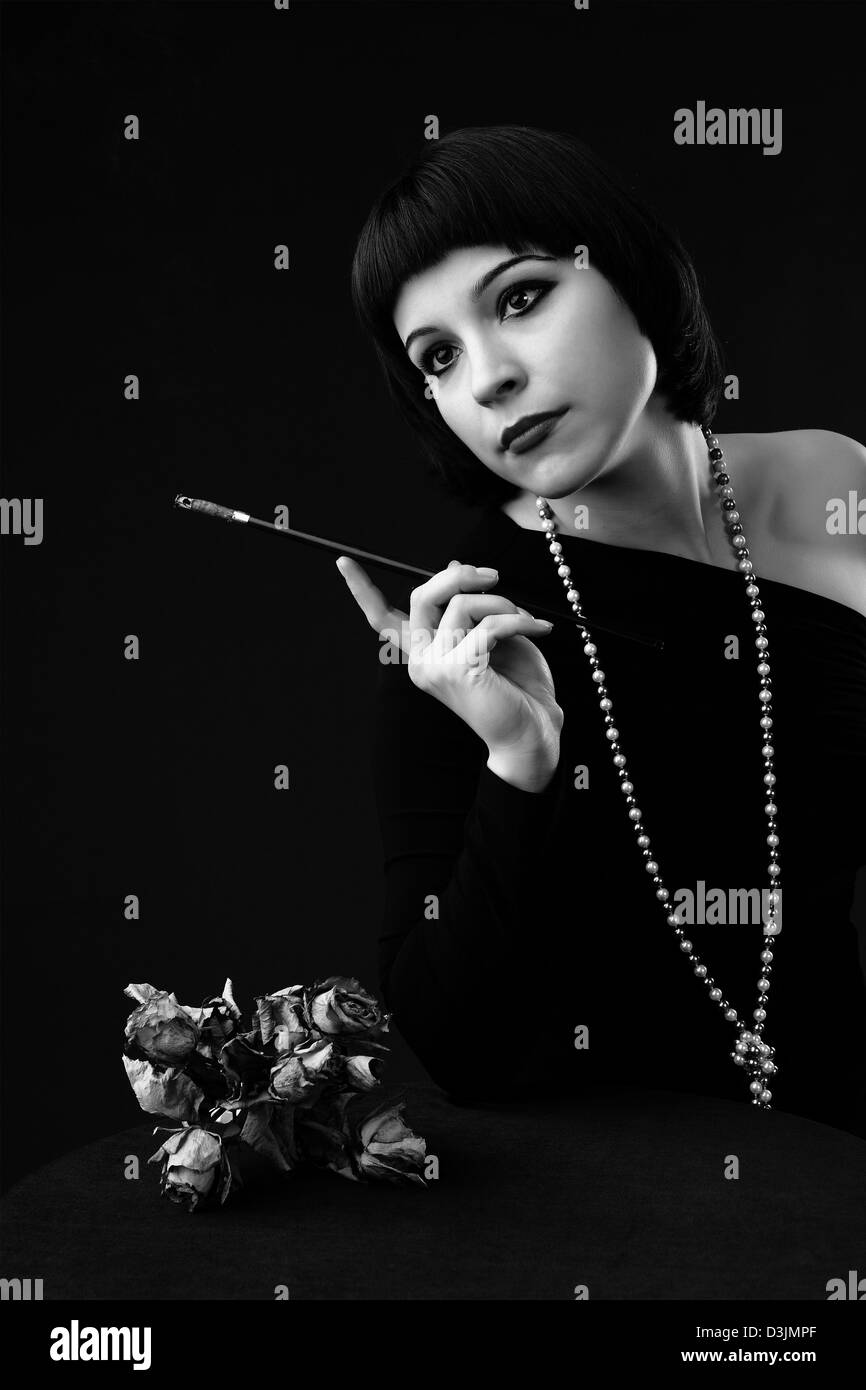 Noir et blanc : vintage styled portrait d'une jeune belle femme avec porte-cigarette Banque D'Images