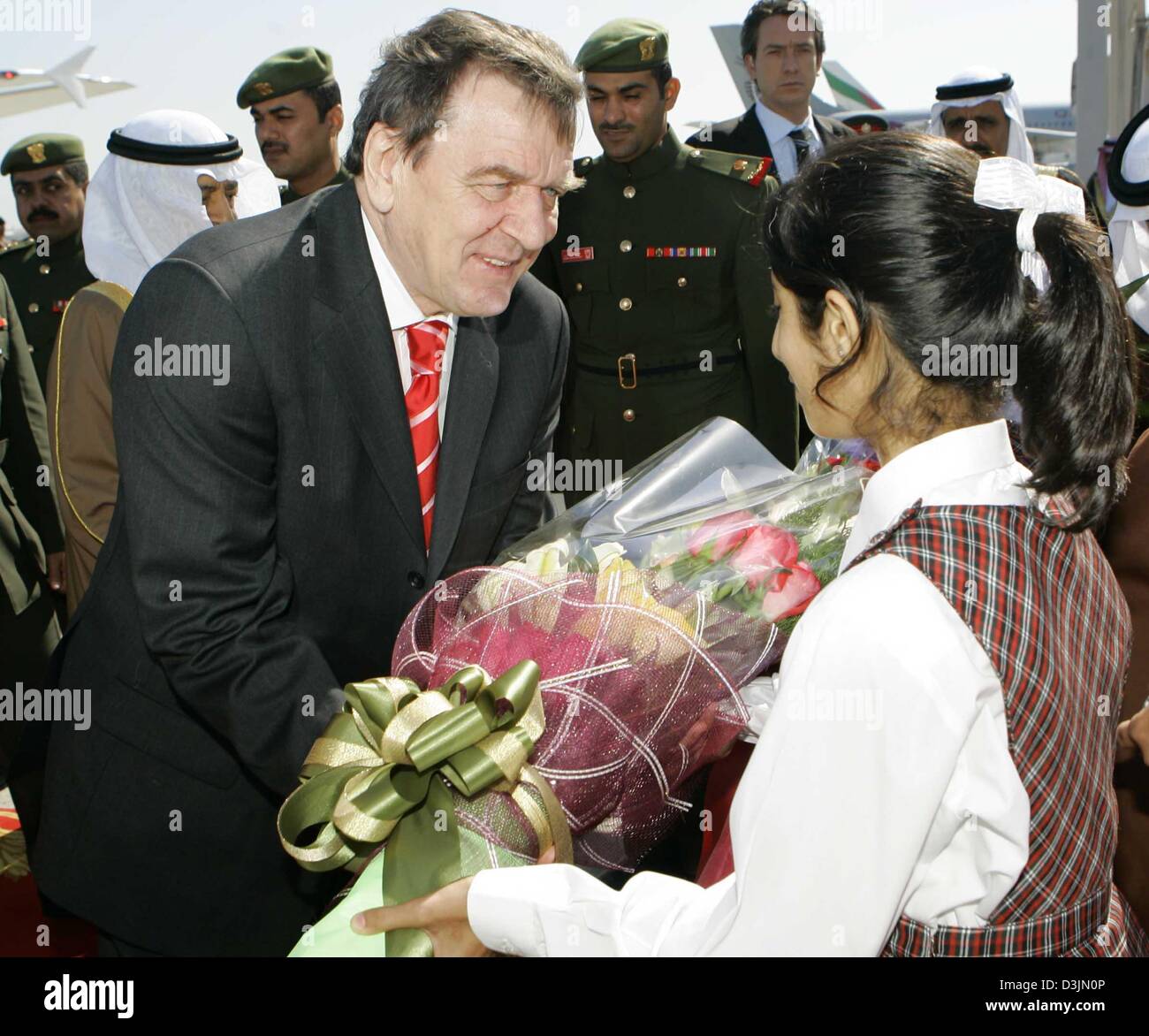 (Afp) - Le Chancelier allemand Schroeder est accueilli par une jeune fille avec des fleurs à l'aéroport de Manama, Bahreïn, le 2 mars 2005. Schroeder visite à Bahreïn est partie de sa tournée d'une semaine de sept pays arabes visant à stimuler l'Allemagne Les relations politiques et commerciales dans la région du Golfe. Banque D'Images
