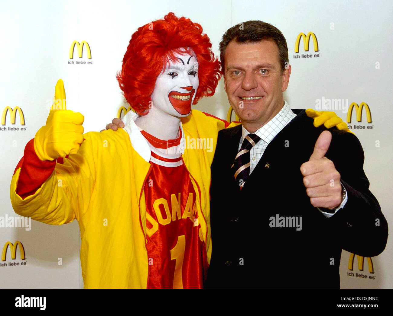 (Afp) - Adriaan Hendrikx (R), manager de la division allemande de la chaîne de fast-food McDonald's et la société Ronald McDonald, la mascotte de donner un coup de pouce et sourire au cours d'une conférence de presse bilan à Munich, Allemagne, le mardi 22 février 2005. La société et ses franchisés ont réussi à augmenter le chiffre d'affaires de 1,5 pour cent dans l'exercice 2004. Banque D'Images