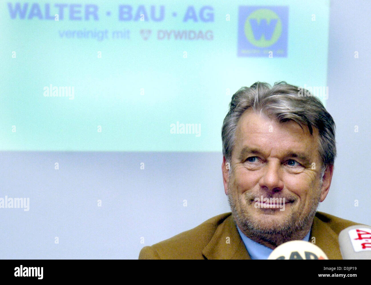 (Afp) - Hans Peter Haselsteiner autrichienne de l'entreprise de construction Strabag sourit devant le logo de l'insolvable Walter Bau AG qui est projetée sur le mur en arrière-plan lors d'une conférence de presse à Augsburg, Allemagne, 15 février 2005. Strabag prendra une part significative de Walter Bau AG notamment autour de 4 100 employés. Walter Bau dispose actuellement d'un total d'environ 9 Banque D'Images