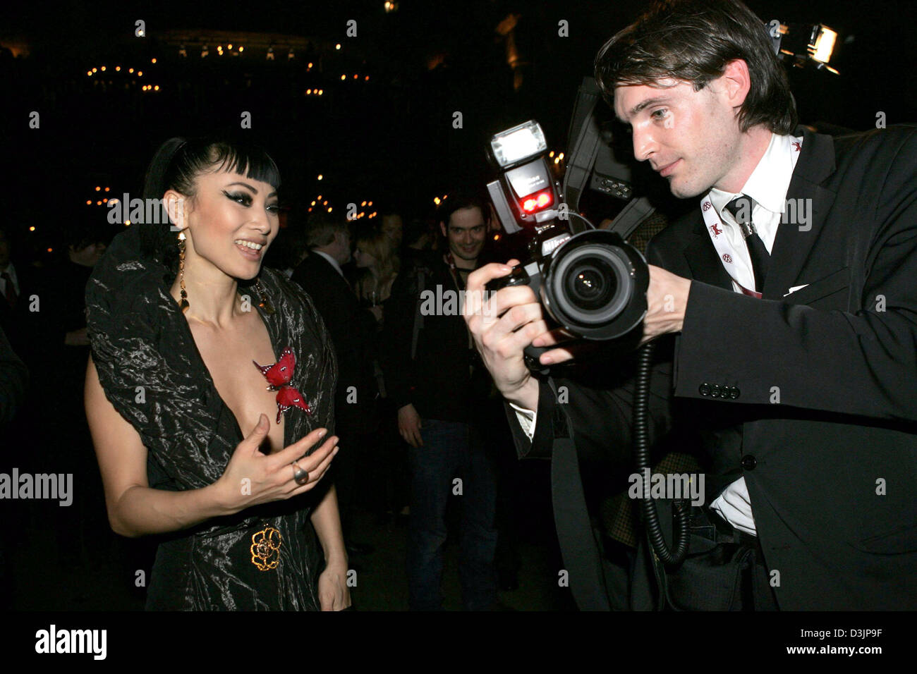 (Afp) - L'actrice chinoise Bai Ling, et membre du jury de la Berlinale, est intéressé par l'appareil photo qui appartient à l'un des photographes lors d'une partie de l'ouverture du 55e festival international du film de Berlin à Berlin, Allemagne, 10 février 2005. Le Festival International du Film, qui se déroule jusqu'au 20 février, dispose d'un total de 350 films de 52 pays avec 22 films en compétition fo Banque D'Images