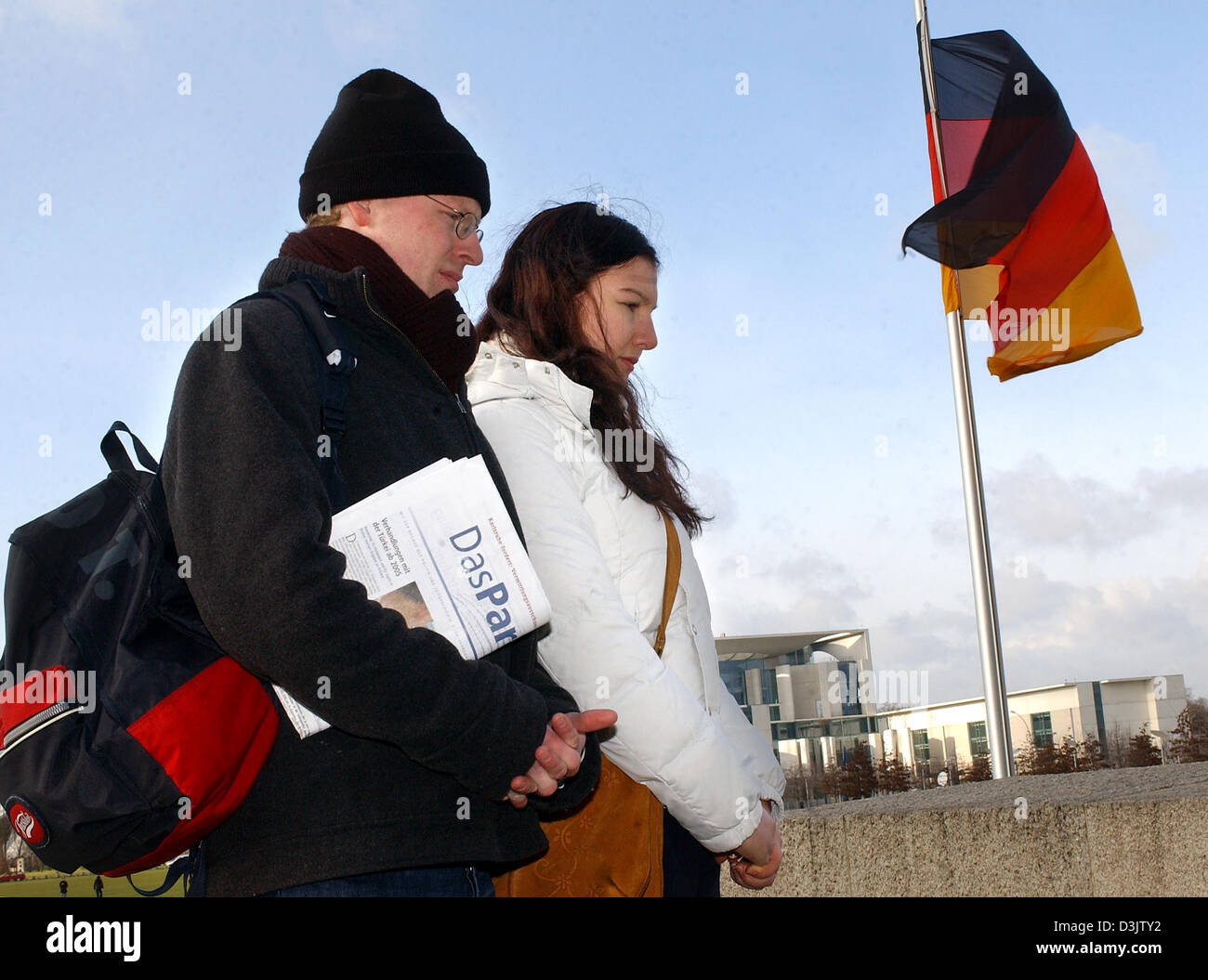 Avec le drapeau allemand en berne dans l'arrière deux piétons pendant une minute de silence en face de la chancellerie à Berlin, Allemagne, le mercredi 5 janvier 2005. Toute l'Europe, les victimes de la catastrophe du tsunami en Asie du sud ont été commémorés par une minute de silence à 12 heures le mercredi. Même la radio et stations de télévision ont participé à la commémoration. Banque D'Images
