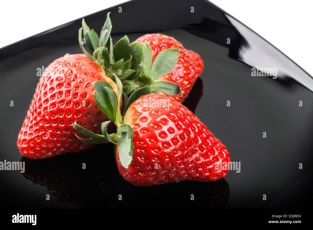 Trois fraises sur soucoupe noire Banque D'Images