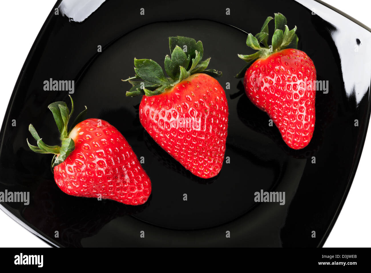 Trois fraises sur noir soucoupe, vue d'en haut Banque D'Images