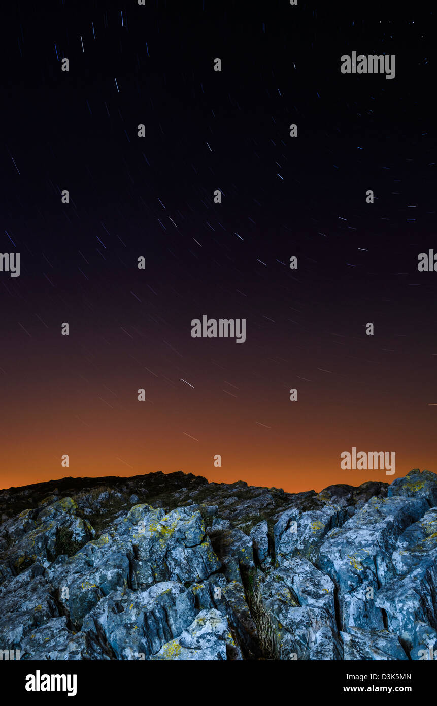 Des étoiles sillonnent l'affleurement calcaire de Crook Peak dans les collines de Mendip la nuit près d'Axbridge, Somerset, Angleterre. Banque D'Images