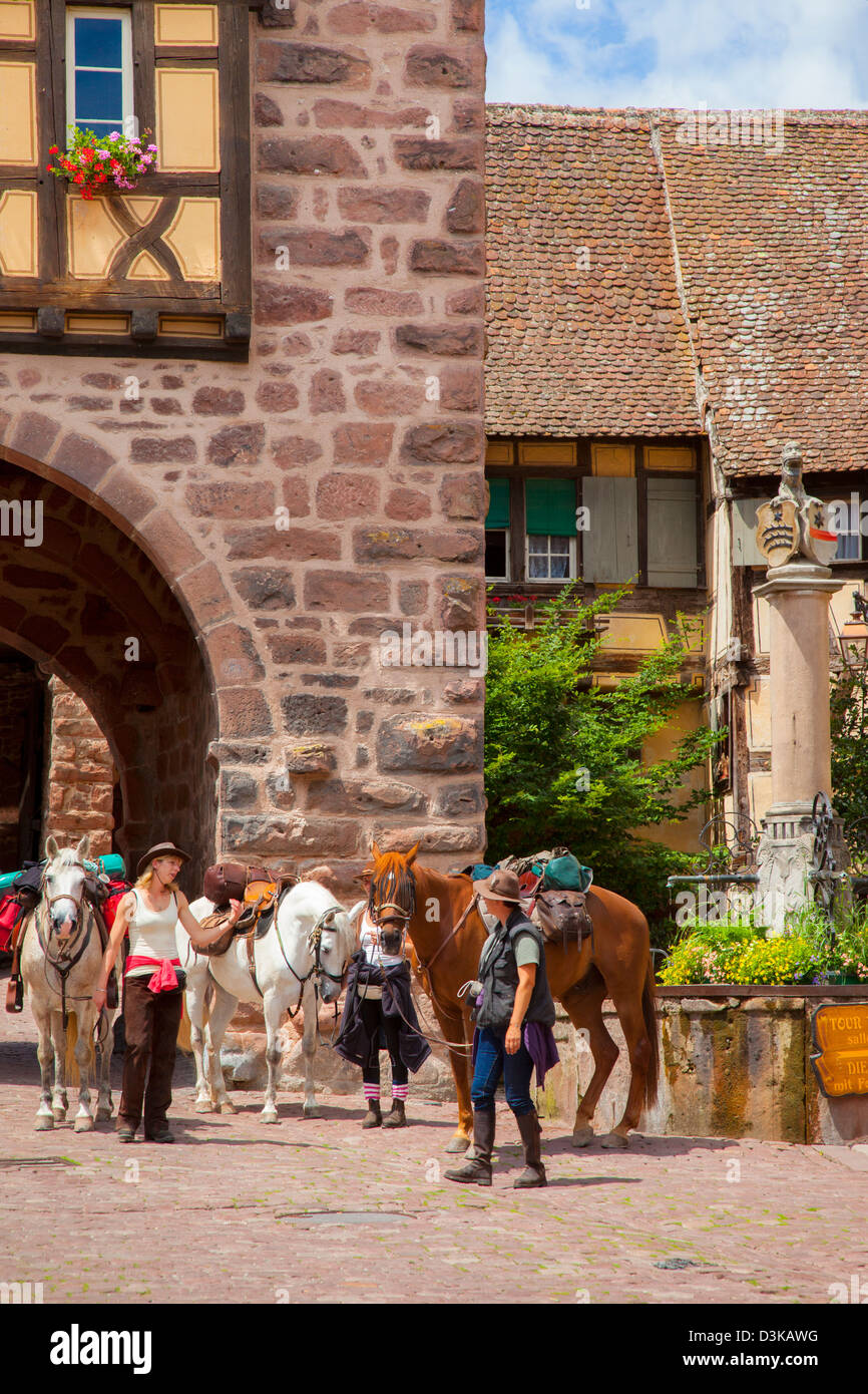 Les femmes avec des chevaux de selle à la fontaine publique de Riquewihr, le long de la Route des Vins (Route des Vins), Alsace France Banque D'Images