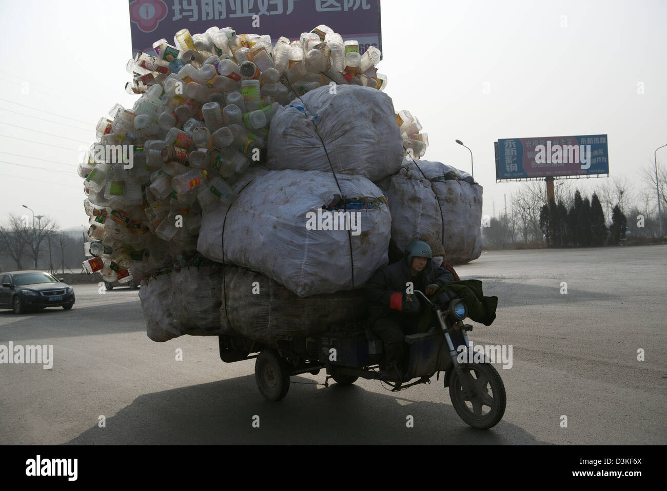 Un tricycle à moteur chargé avec des bouteilles en plastique recyclable durs le long d'une rue dans une ville dans la province de Hebei, Chine. 17-Feb-2013 Banque D'Images