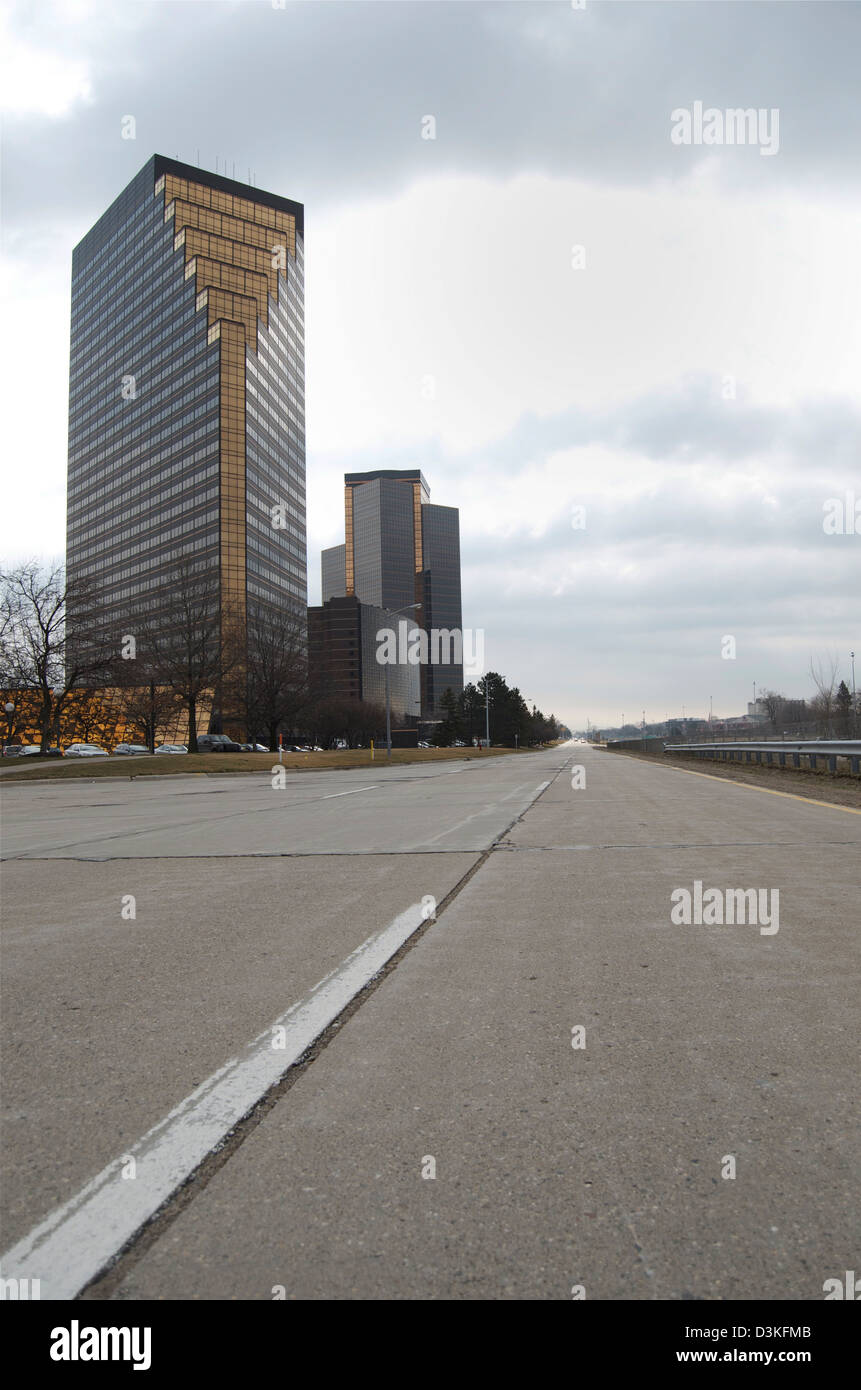 Low angle shot avec la chaussée ouverte au premier plan, ligne blanche et des bâtiments sur la gauche, sous le ciel gris. Banque D'Images