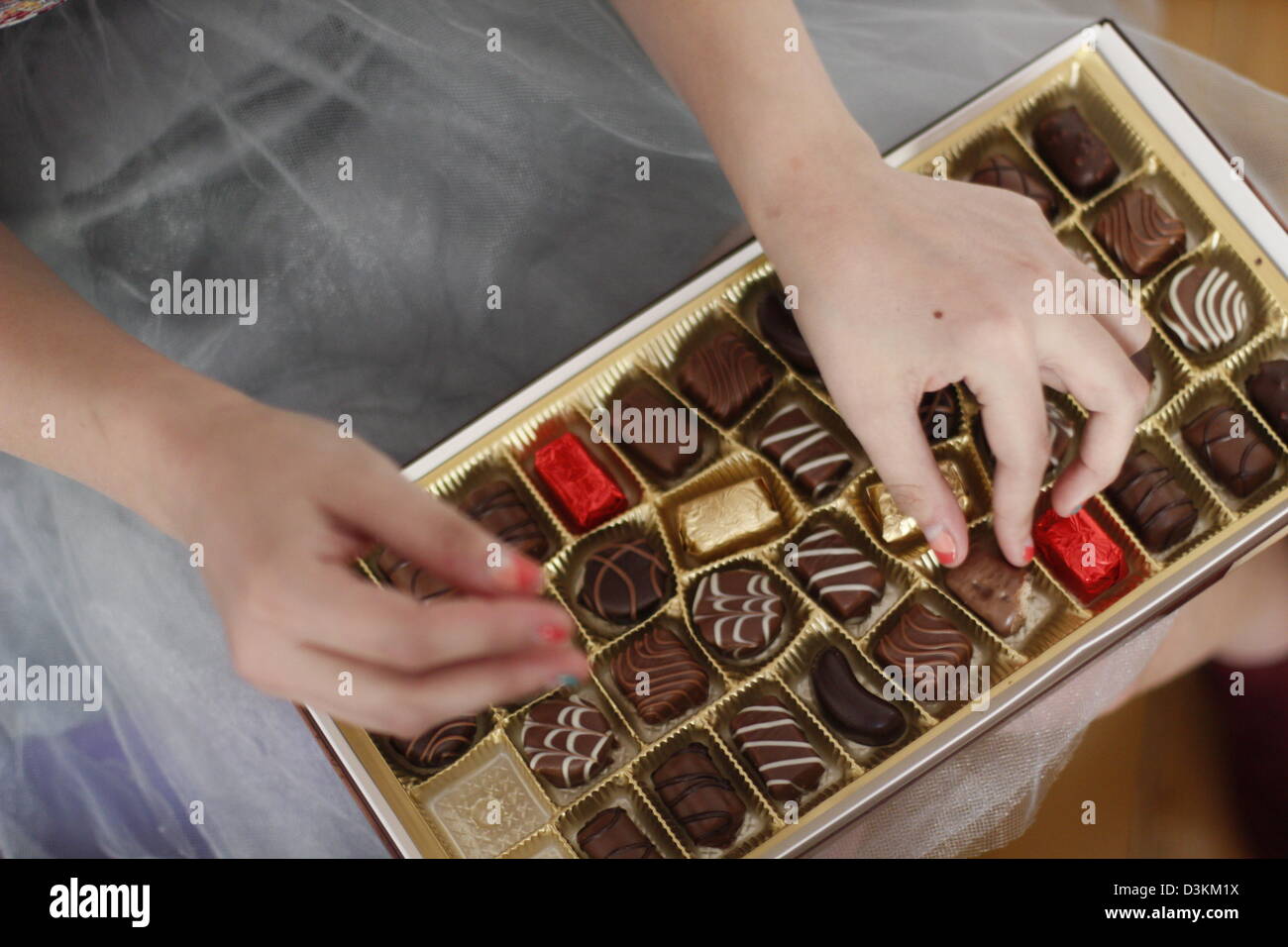 Mains d'une jeune femme ramasser une boîte de chocolats à Bucarest, Roumanie. Banque D'Images