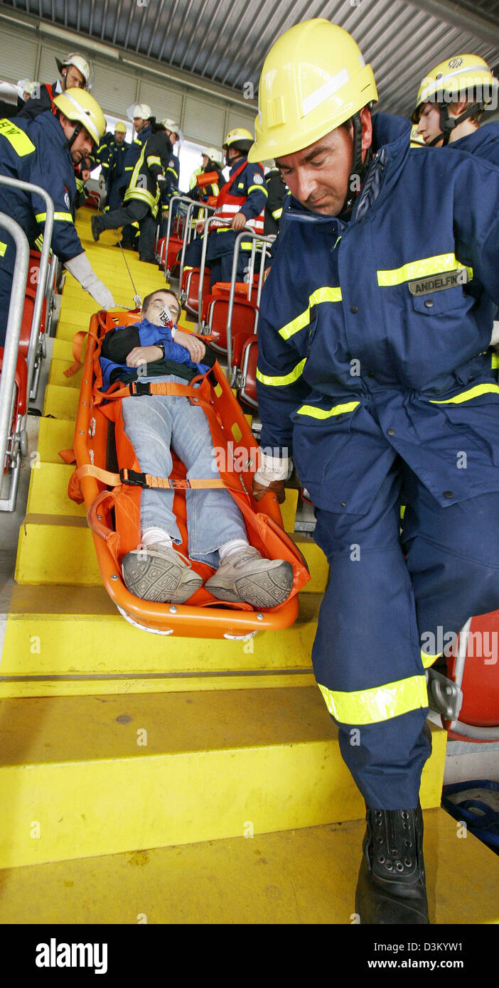 (Afp) - Le sauvetage des pompiers de l'un des figurants dans une civière durant la pratique d'urgence au Fritz Walter stadium à Kaiserslautern, Allemagne, samedi 08 octobre 2005. Plus de 800 membres du personnel des forces de police, pompiers et services de secours ont pris part à la pratique pour se préparer pour le pire des cas au cours de la monde de football en 2006. Photo : Ronald Wittek Banque D'Images