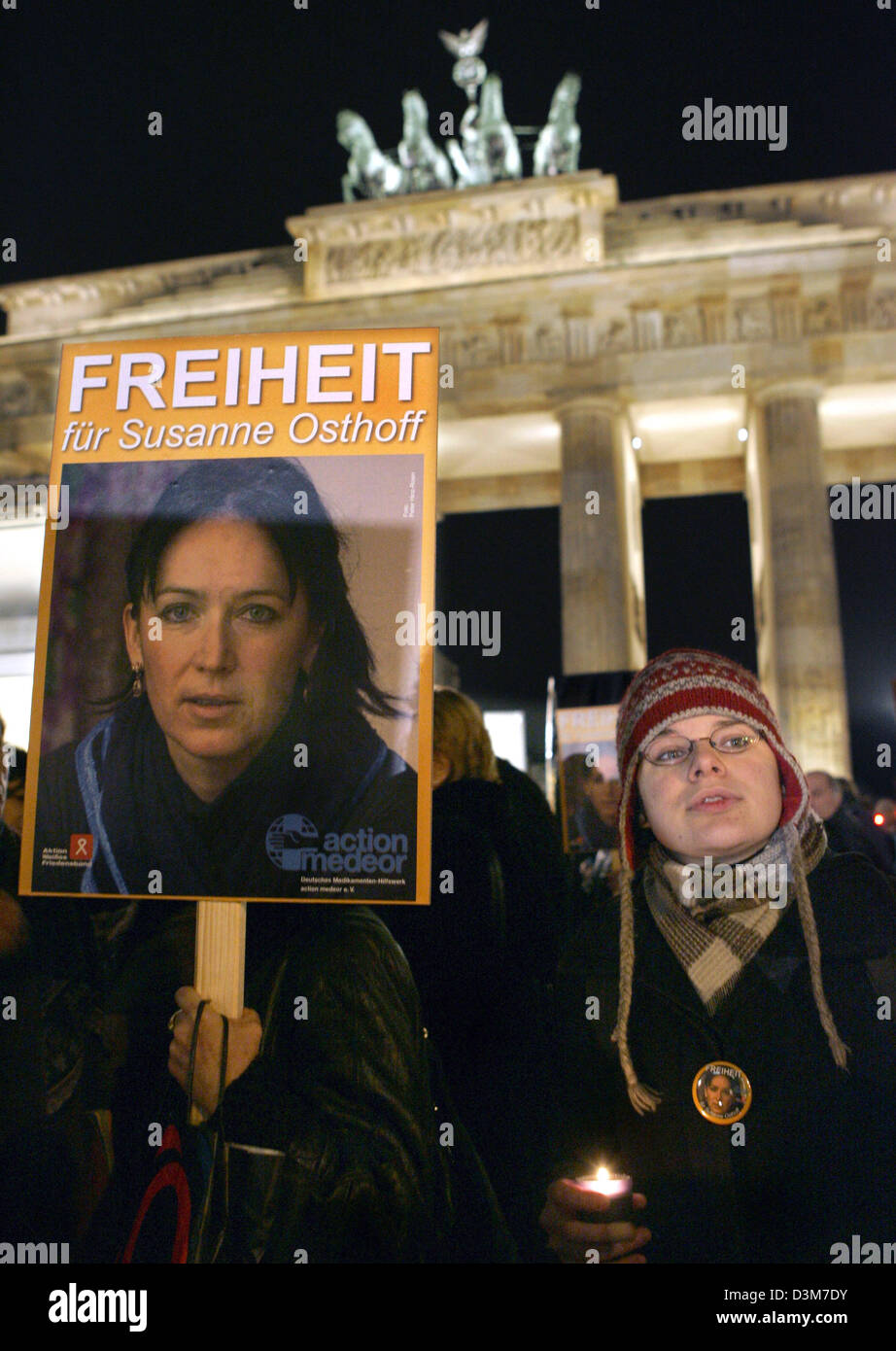 Une femme tenant une bougie allumée dans sa main, se tient à côté d'une affiche présentant le portrait de Susanne Osthoff kidnappé lors d'un des vigiles solennelles en son nom devant la porte de Brandebourg à Berlin, mercredi, 14 décembre 2005. L'archéologue allemand a été enlevée par des inconnus en Irak le 25 novembre 2005. Banque D'Images