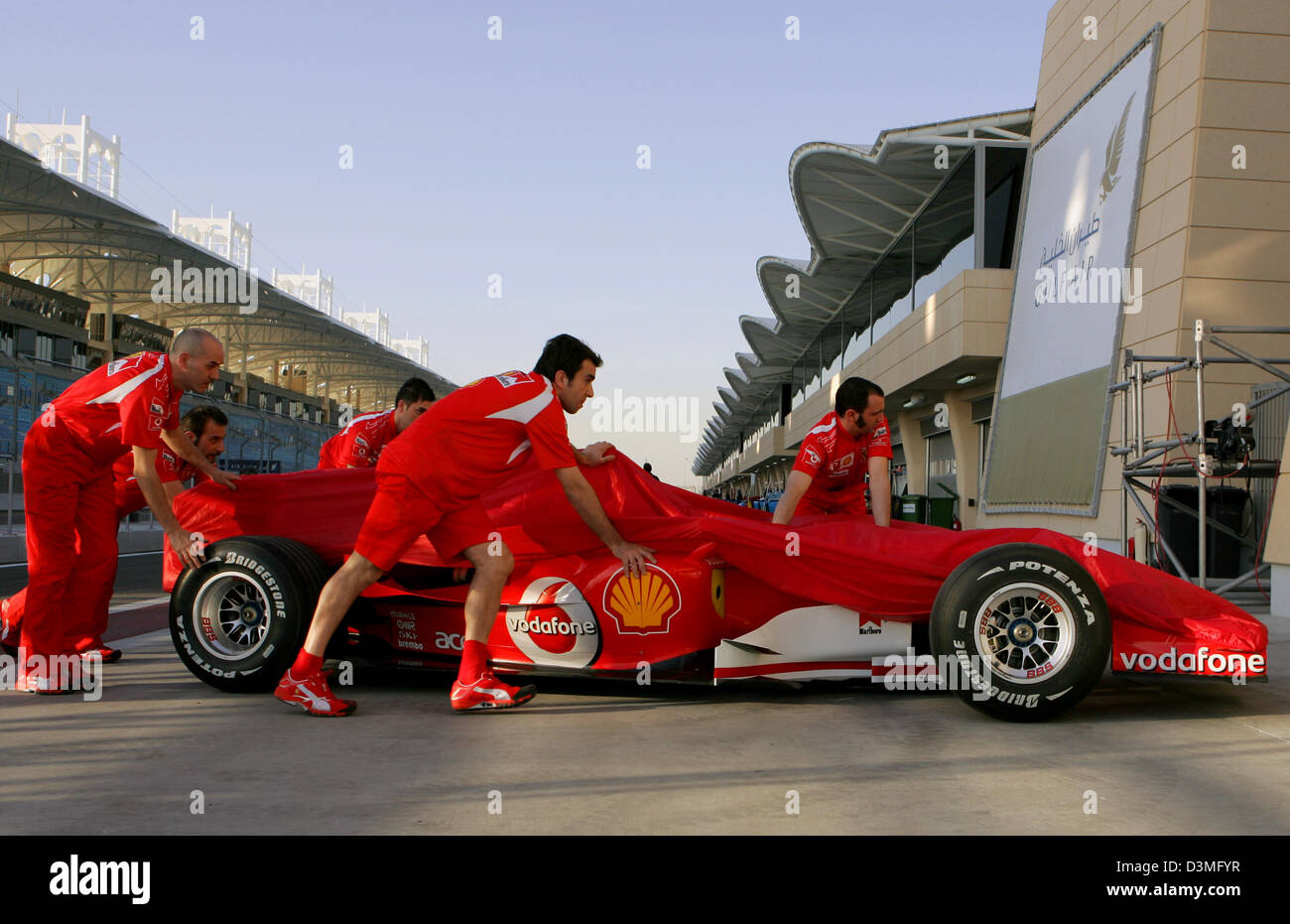 Mécanique de Ferrari pousser leur voiture dans la voie des stands à la piste de course de Formule 1 près de Manama, Bahreïn, le mercredi 08 mars 2006. La première course du championnat du monde de F1 2006, le Grand Prix de Bahreïn, aura lieu ici le dimanche 12 mars 2006. Photo : Carmen Jaspersen Banque D'Images