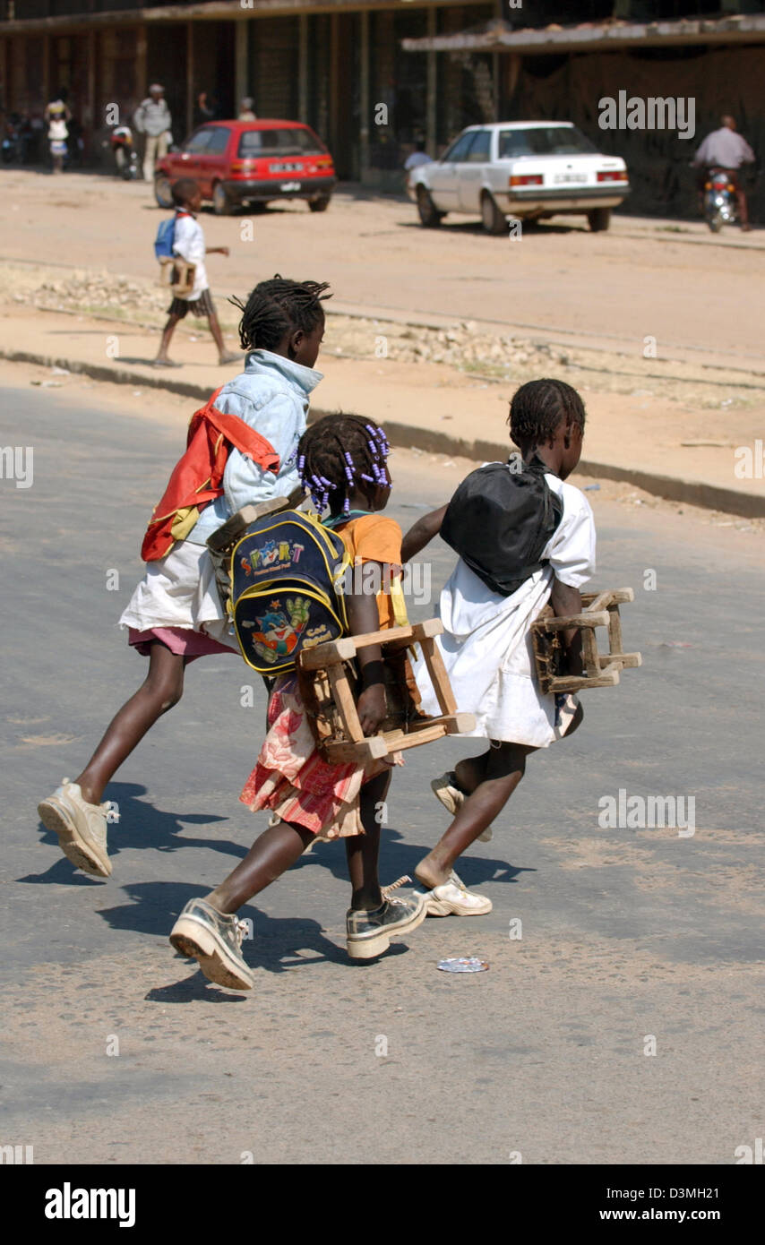 (Afp) - Les enfants de traverser une rue ravagée par la guerre dans la province de Huambo, Angola ville, 21 juillet 2005. Photo : Wolfgang Langenstrassen Banque D'Images