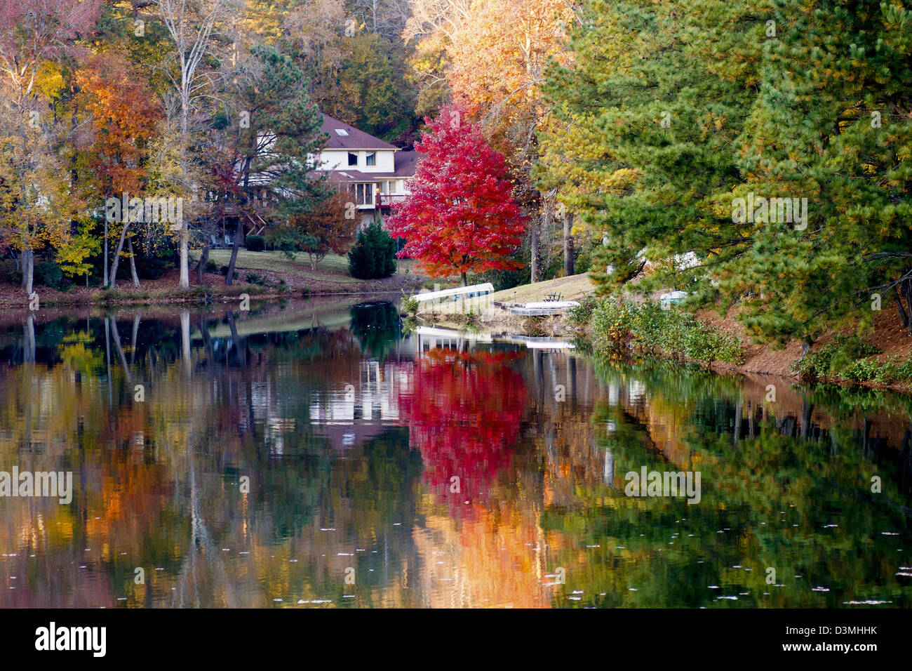 Une belle maison au bord du lac avec eau calme reflétant les arbres d'automne Banque D'Images