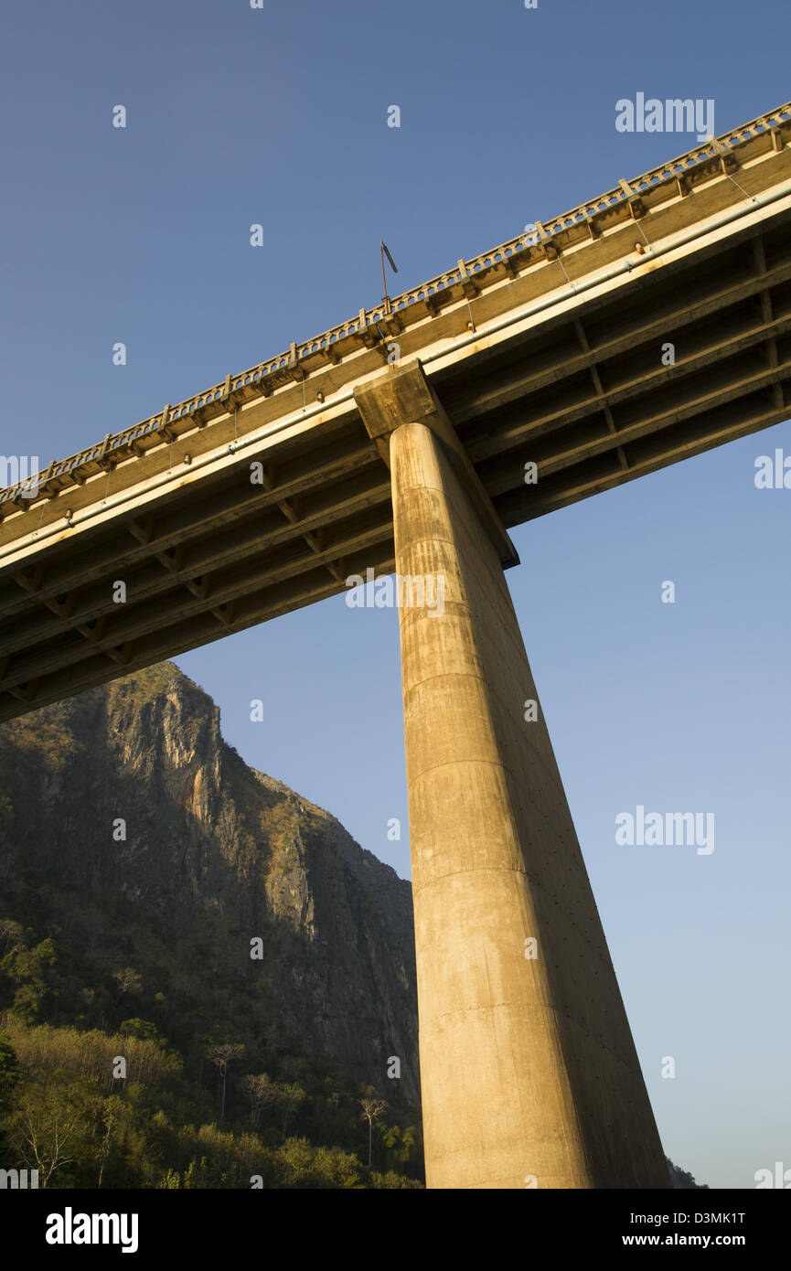 Un pylône de béton et le dessous d'un pont sur une rivière en béton sont visibles contre un ciel bleu à partir de ci-dessous. Banque D'Images