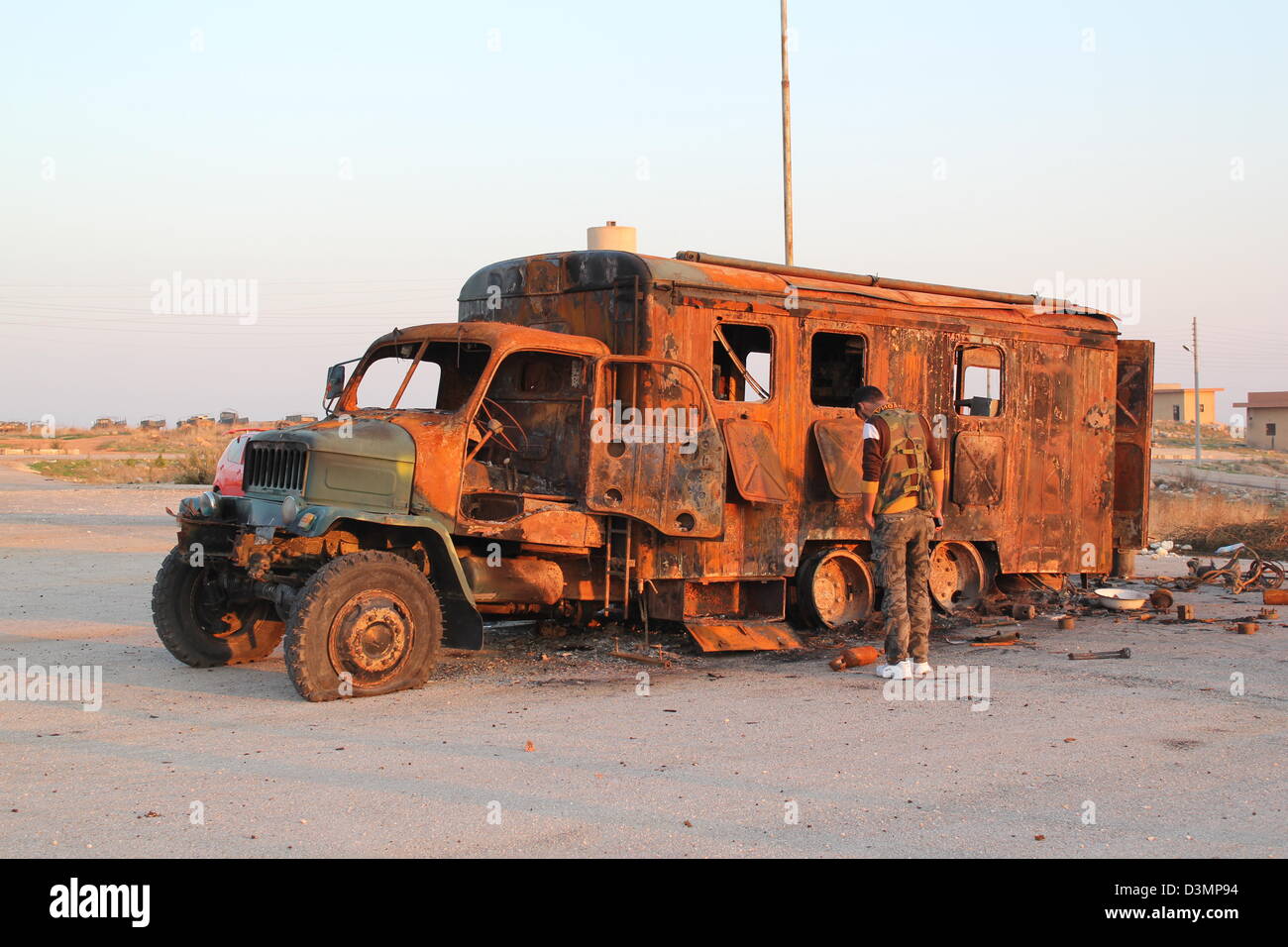 Membre de l'Armée syrienne libre inspecte un véhicule détruit sur une base de l'armée dans le Nord de la Syrie. Banque D'Images
