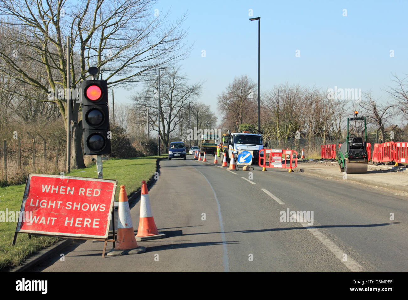 Lorsque la lumière rouge indique attendre ici. Feux de circulation temporaire sur la route de Feltham, England, UK. Banque D'Images