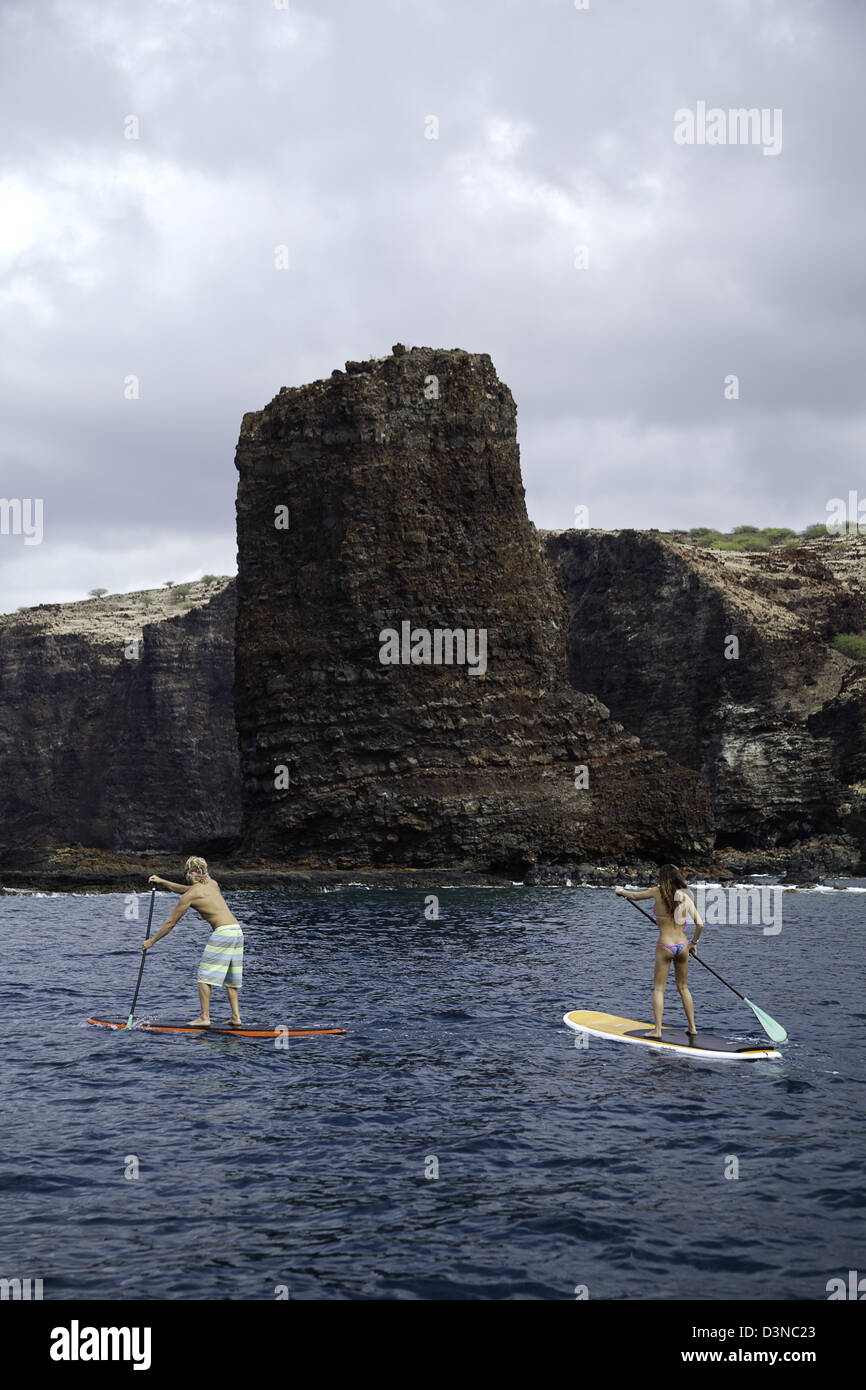 Un jeune couple sur le stand-up paddle boards à aiguilles à l'extérieur de l'île de Lanai, Hawaii. Les deux sont libérés du modèle. Banque D'Images