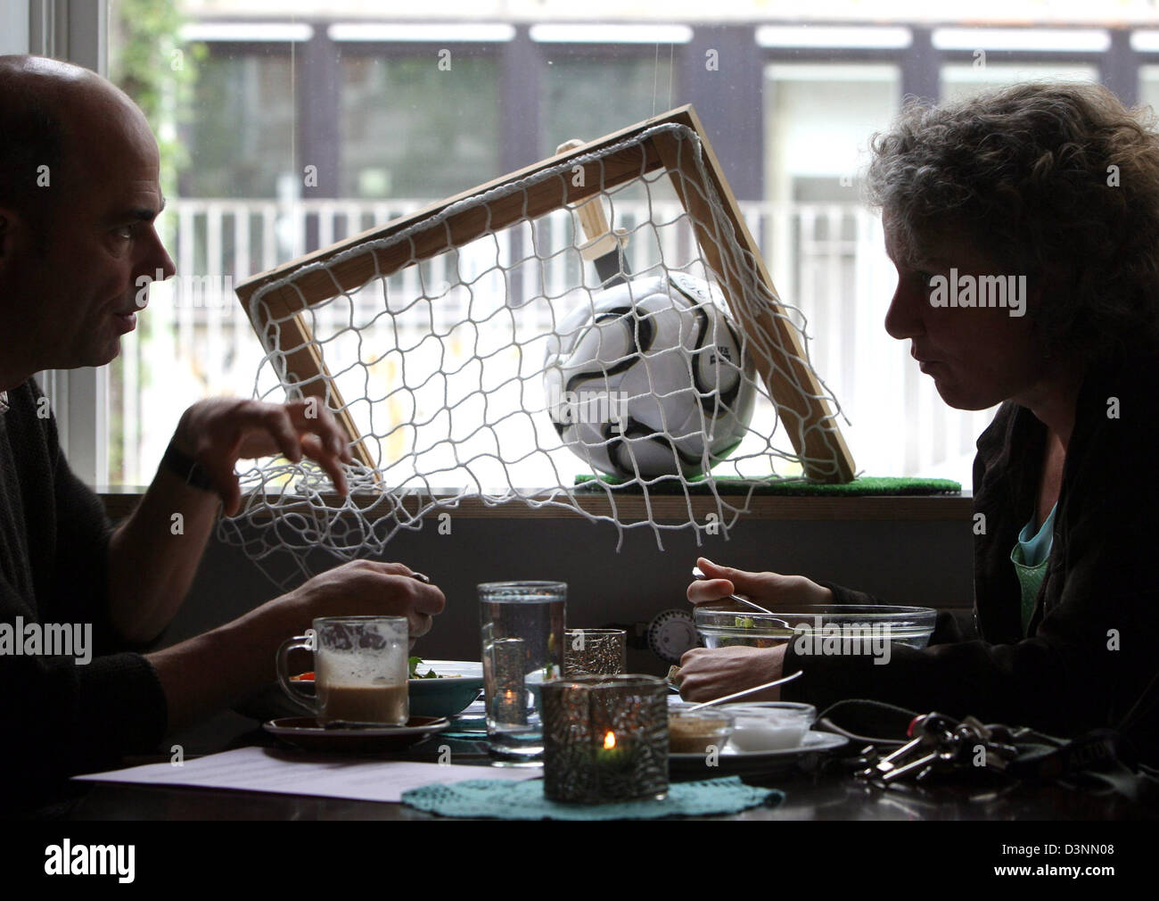 Vous pourrez boire un café dans un café à côté d'un ballon de soccer avec un couteau qui sort dans un café à Hambourg, Allemagne, 30 mai 2006. L 'FuH' dans le quartier Ottensen Hambourg s'est déclaré "zone libre football'. Il vise à offrir des activités de remplacement en particulier pour les veuves de soccer le soccer et à tous ceux qui rejette la hype de football pendant la Coupe du Monde de football. Photo : Kay Nietfeld Banque D'Images