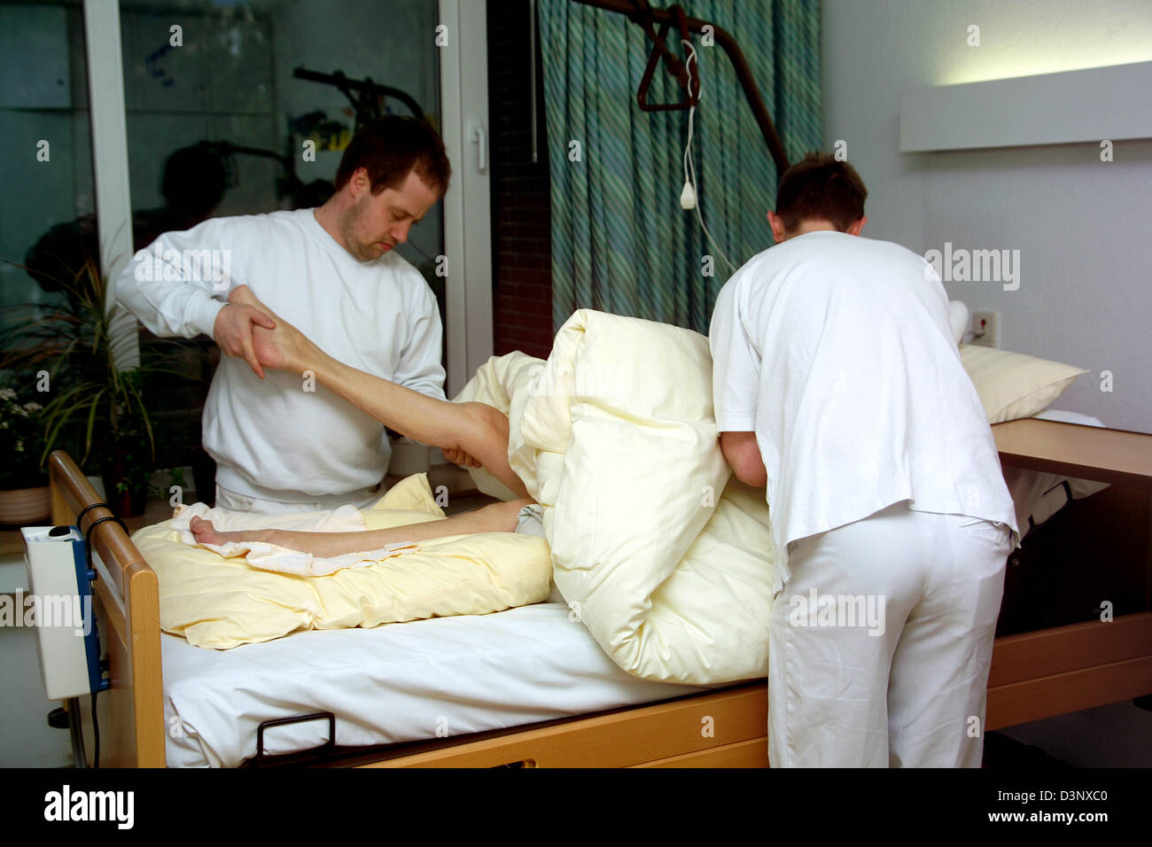 (Afp) Deux soignants pour les personnes âgées montré au cours d'une séance de physiothérapie avec une femme de 97 ans au lit à l'Erna-David-Seniorenzentrum' à Dortmund, en Allemagne, le 11 mars 2005. Photo : Klaus Rose Banque D'Images