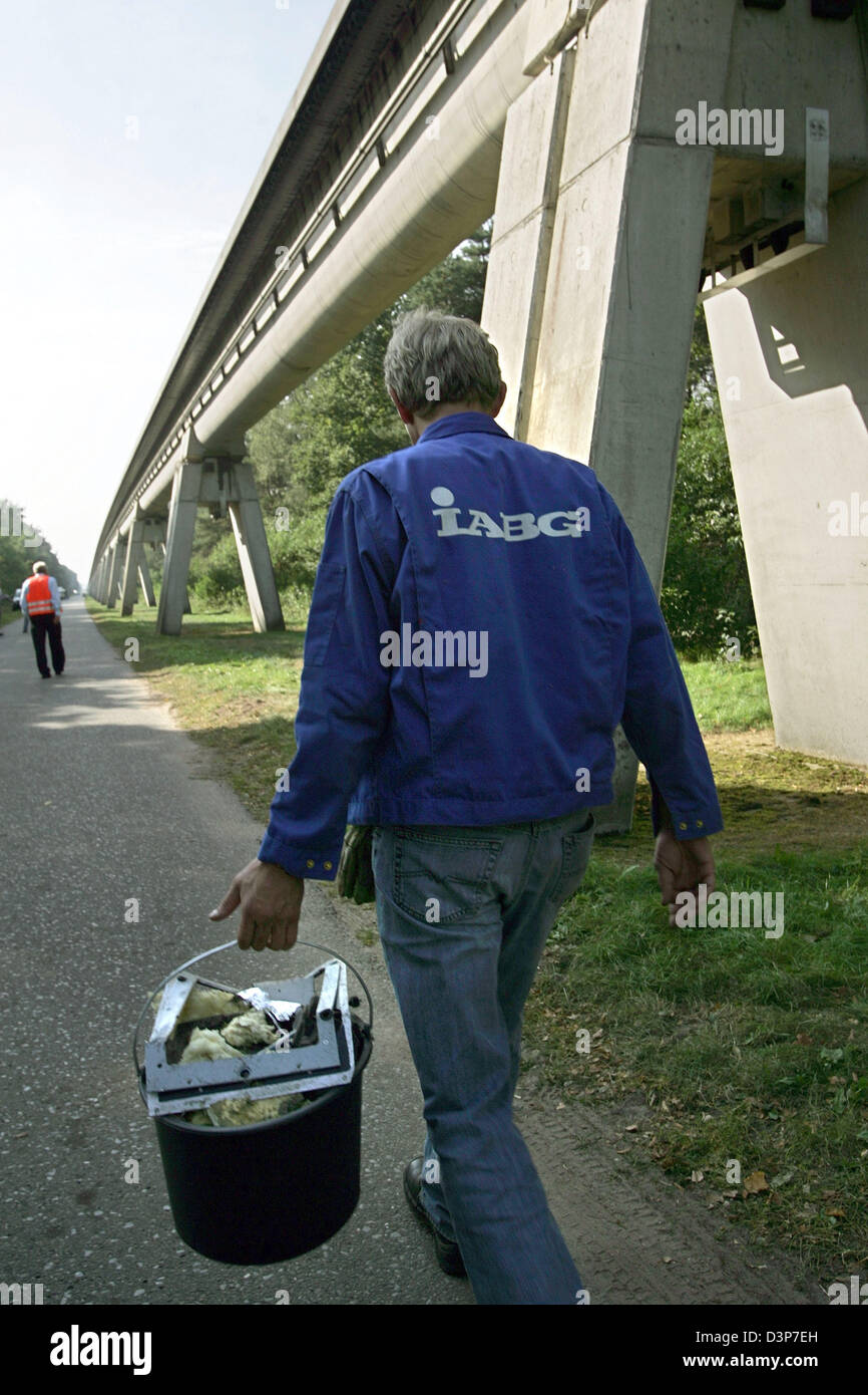 Un employé de l'opérateur et l'IABG Thyssen recueille des petits morceaux de débris du maglev train qui s'est écrasé le 21 septembre 2006 sous la voie 5m au-dessus du sol dans la région de Lathen, Allemagne, lundi 25 septembre 2006. 23 personnes sont décédées. Photo : Ingo Wagner Banque D'Images