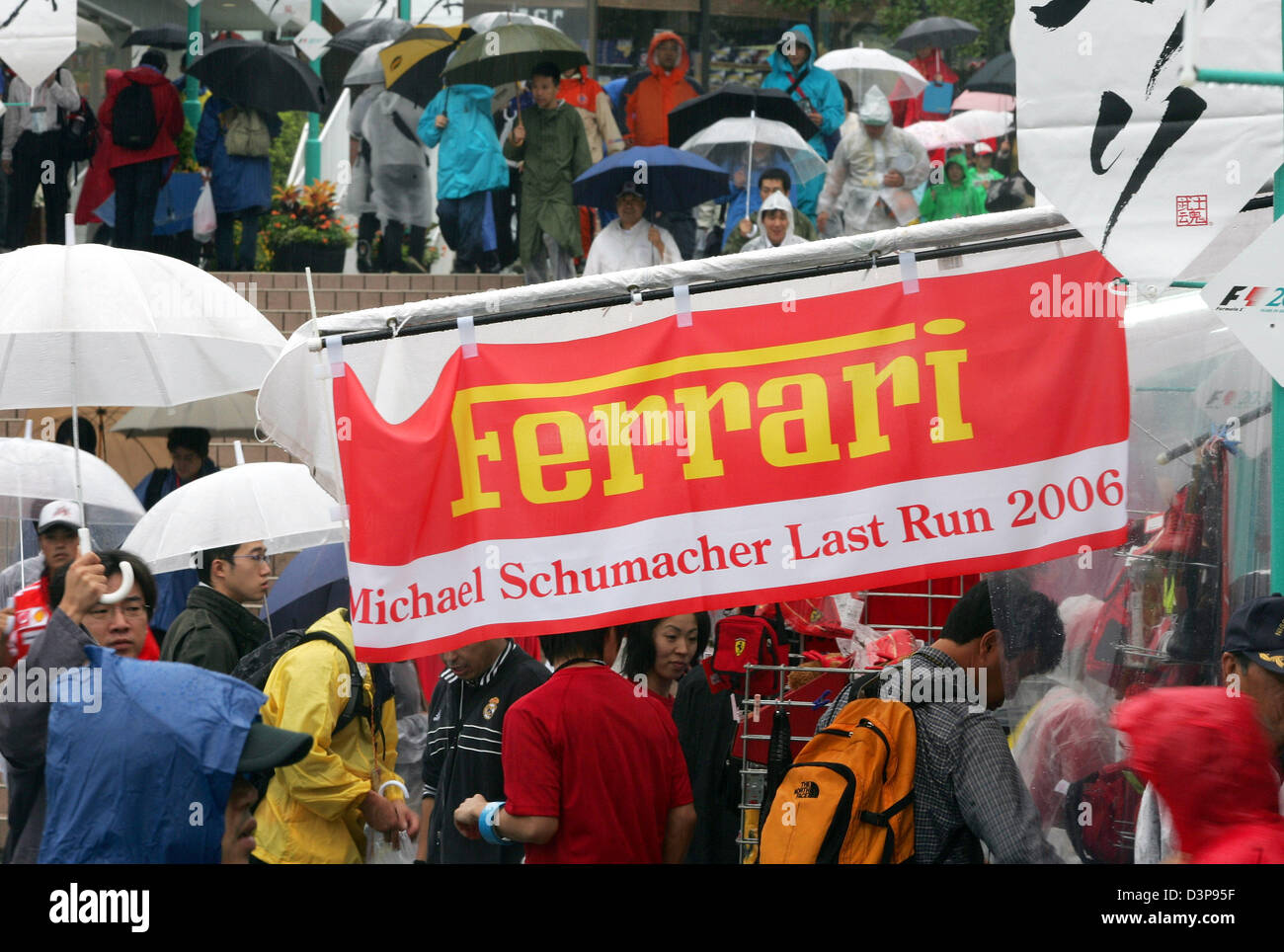 Les spectateurs avec parasols passer une lecture drapeau 'Michael Schumacher dernier run 2006' à la Suzuka International Racing course à Suzuka, Japon, vendredi, 06 octobre 2006. 2006 Le Grand Prix du Japon de Formule 1 aura lieu ici le dimanche, 08 octobre. Photo : Gero Breloer Banque D'Images