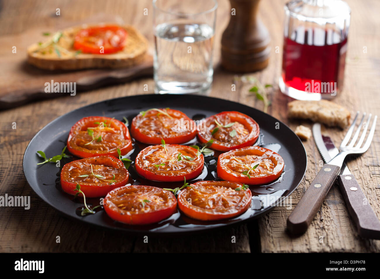 Les tomates cuites au four avec des herbes et d'huile d'olive Banque D'Images