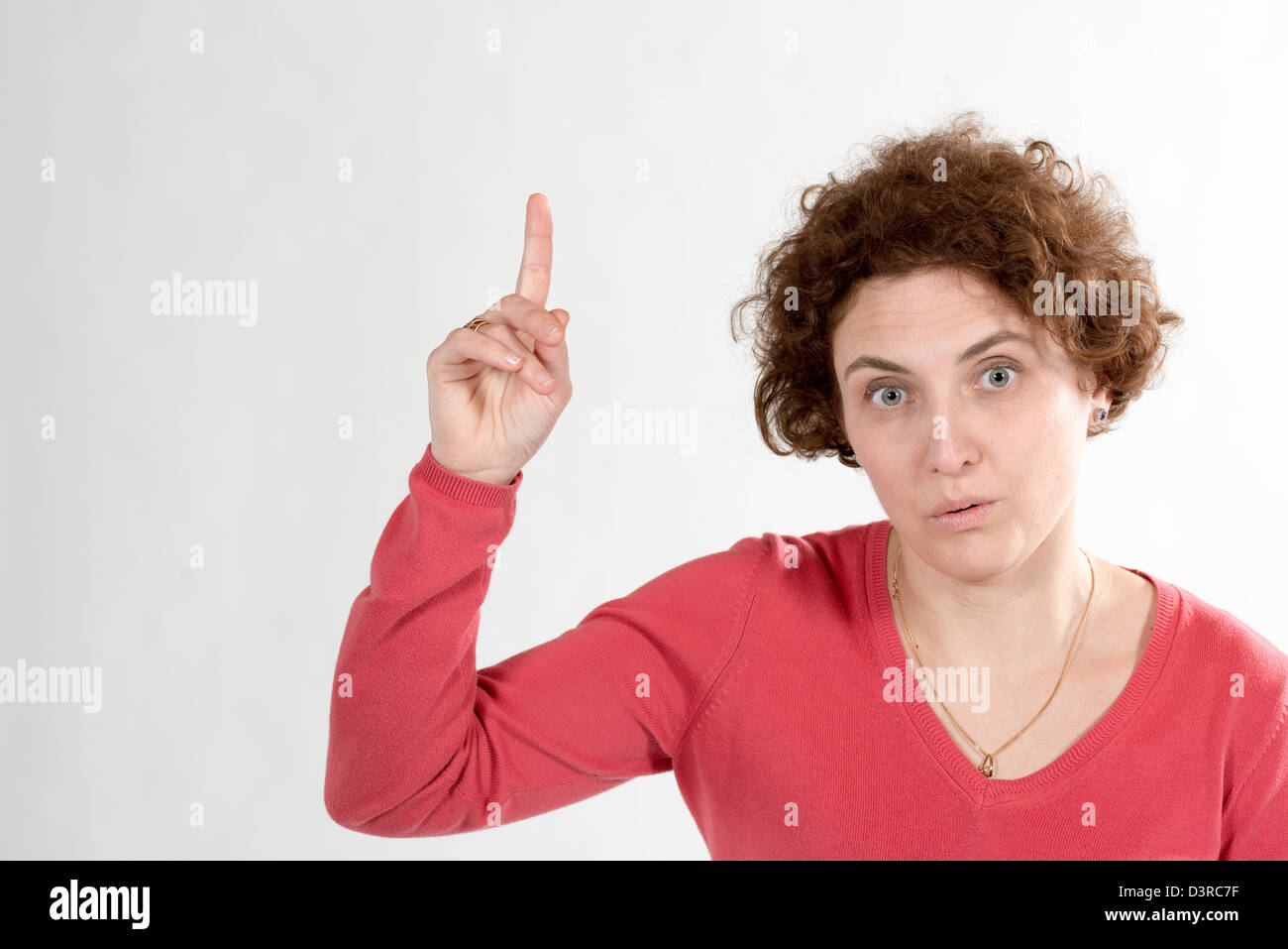 Woman pointing bouclés avec son doigt et donner regard étrange Banque D'Images