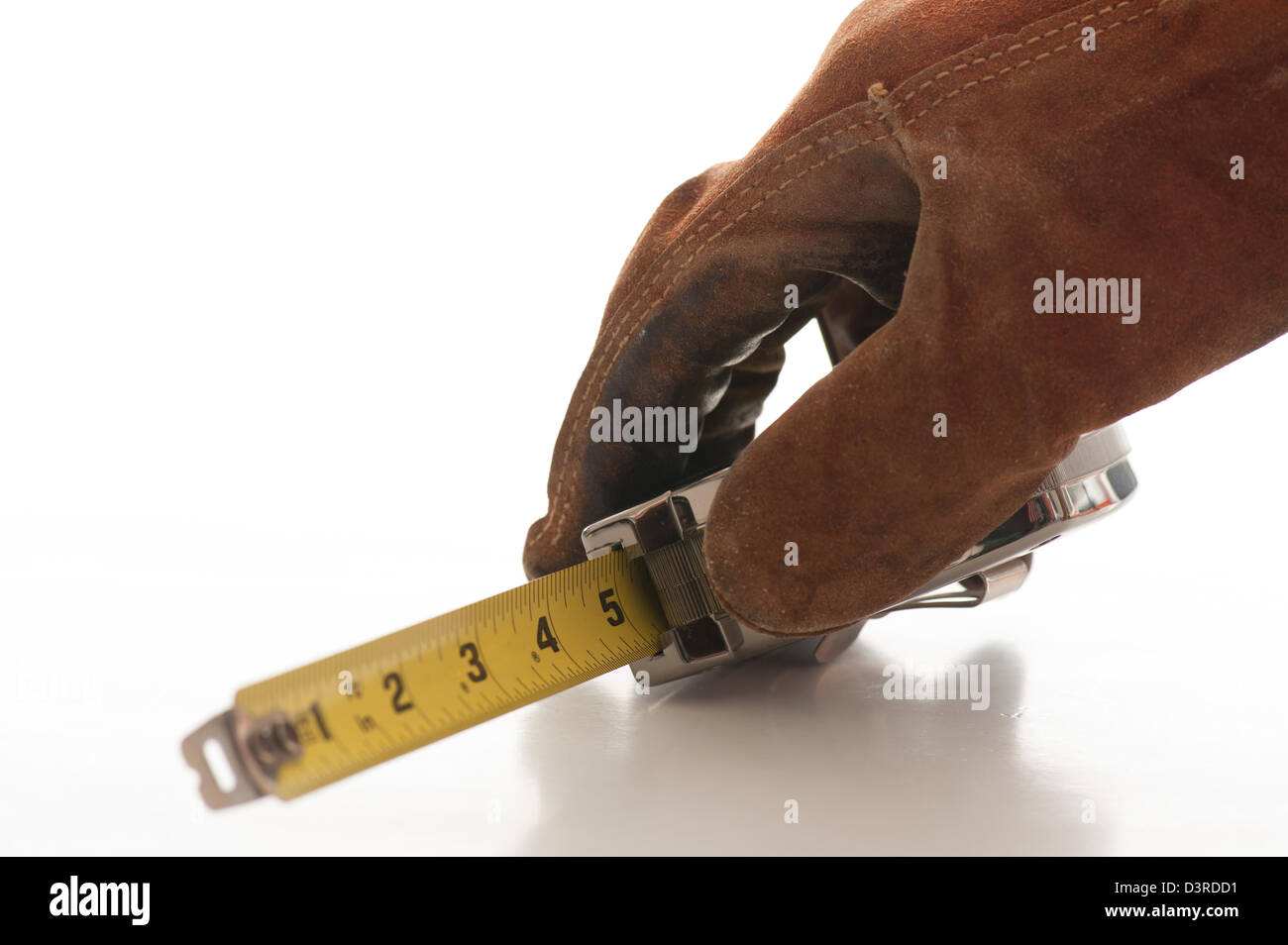 Gloved hand holding mesure de bande en acier Banque D'Images