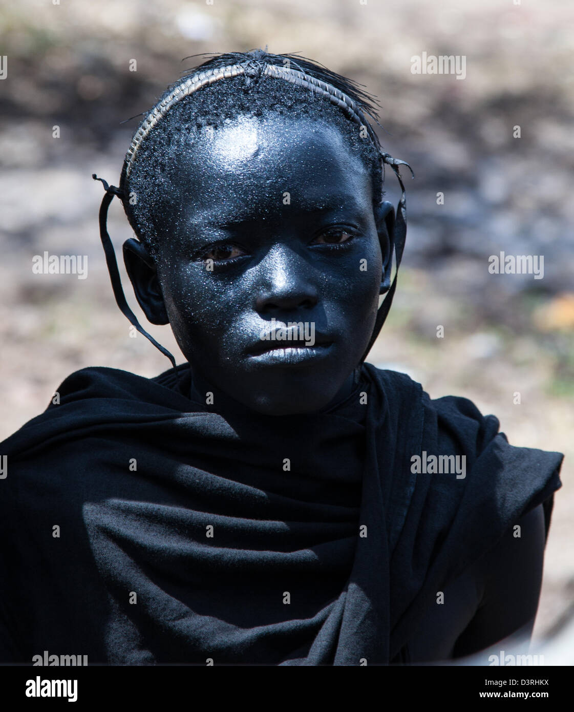 Un adolescent se prépare pour sa vie comme un guerrier Masaï. La peinture du visage traditionnels des garçons qui ont récemment été cercumcized. Parc national de Serengeti, Tanzanie Banque D'Images