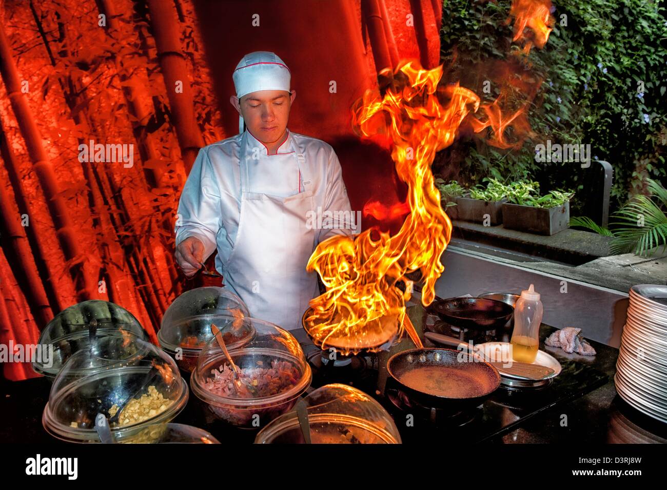 Chef cuisinier au restaurant prépare des feux & omelette pan sur le feu avec des flammes jusqu' Banque D'Images
