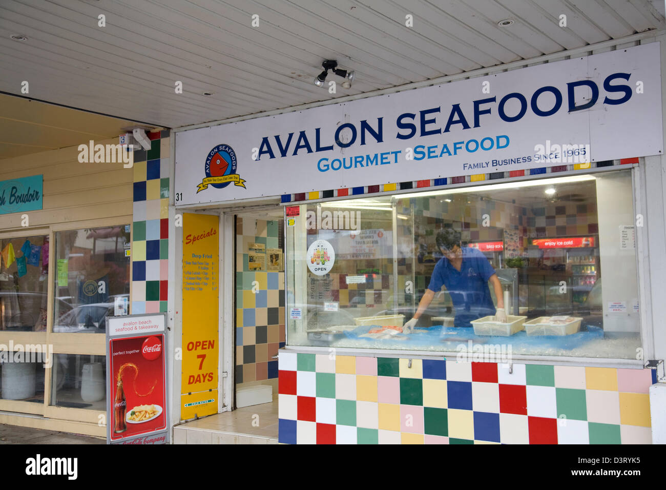 L'homme pose des poissons frais en poissons de Sydney et d'un chip shop store,l'Australie Banque D'Images