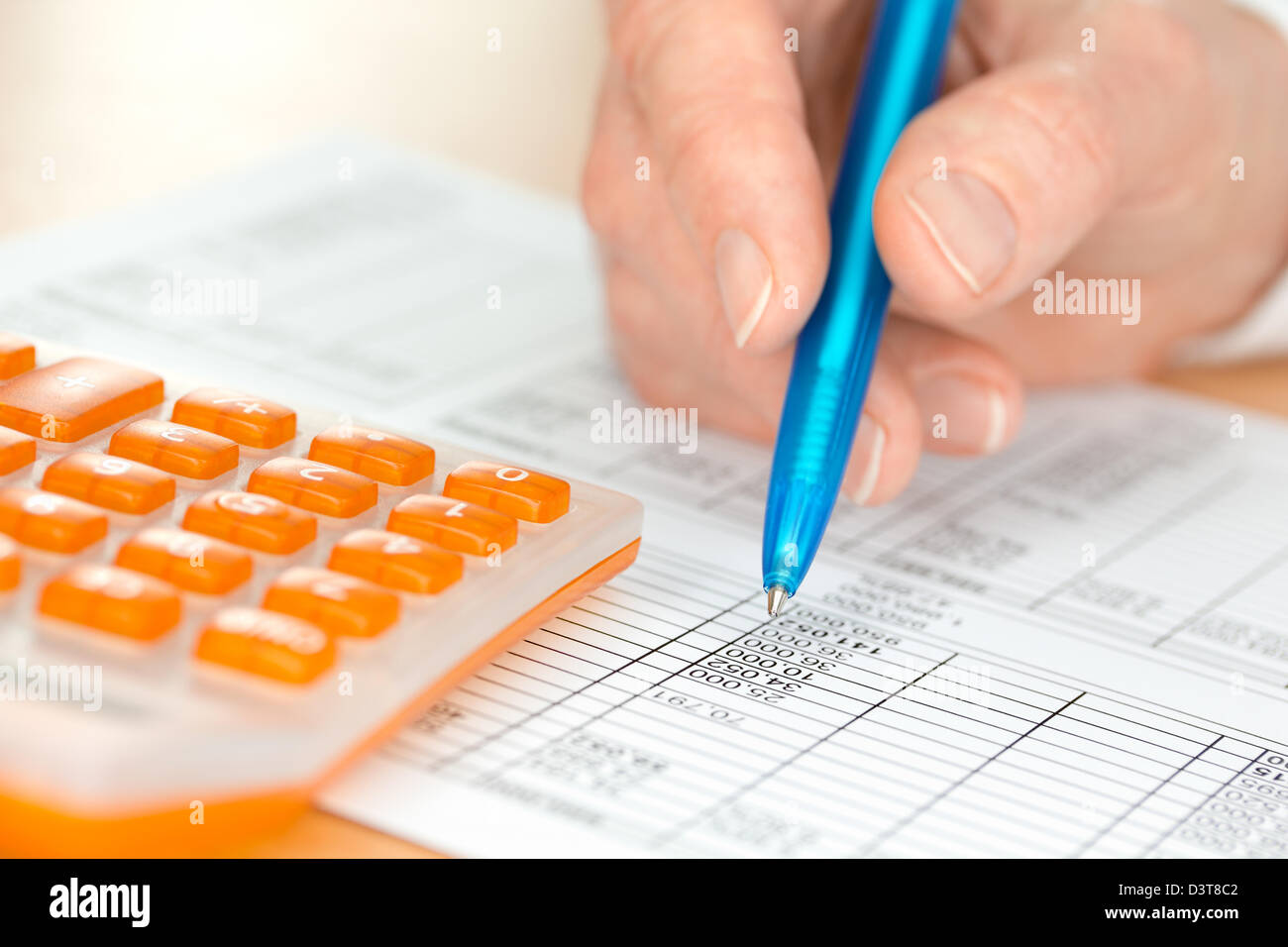 La main avec les numéros de contrôle de stylo bleu par Orange Calculator Banque D'Images