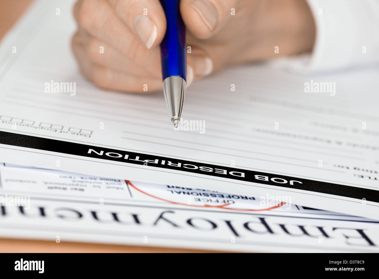 La main avec Pen écrit une description de travail pour l'employé Banque D'Images